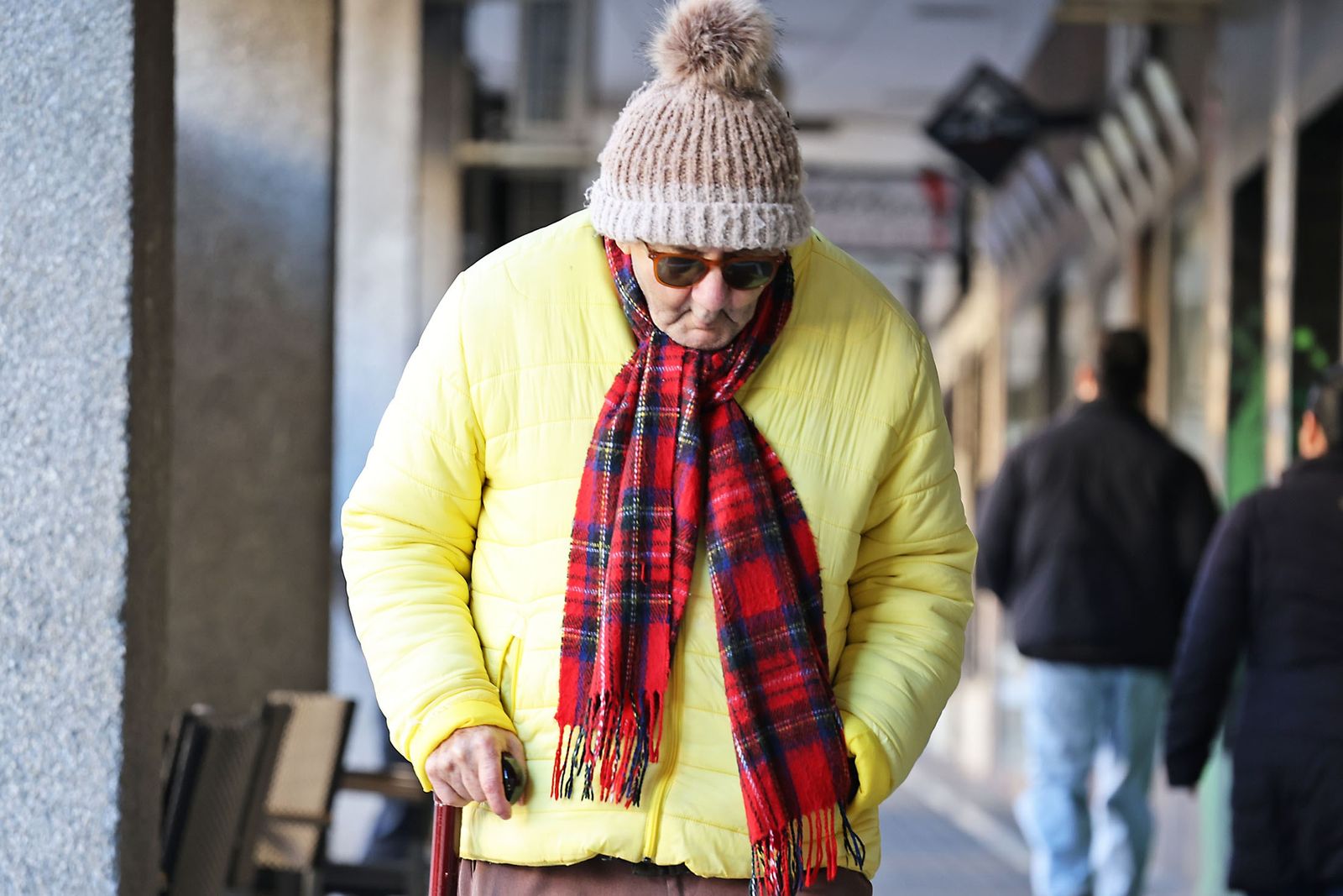 Un señor con gorro, bufanda y abrigo para refugiarse del frío en Huelva.