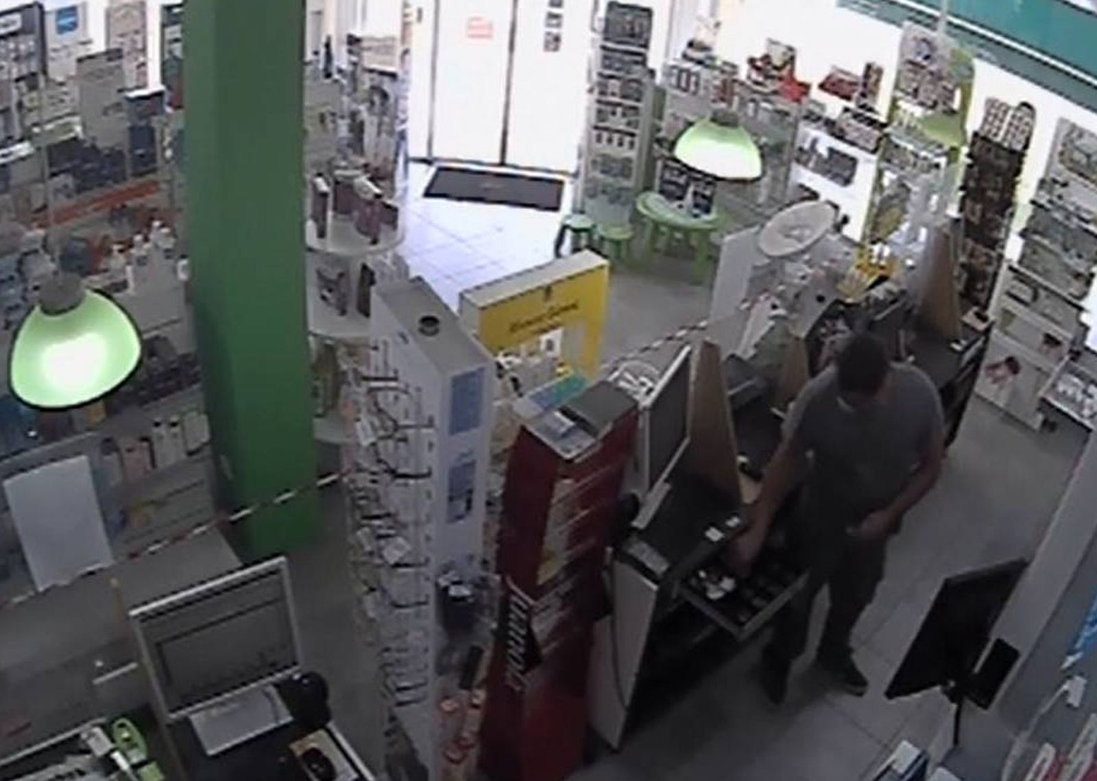 El atracador robando el dinero de la caja de una farmacia.