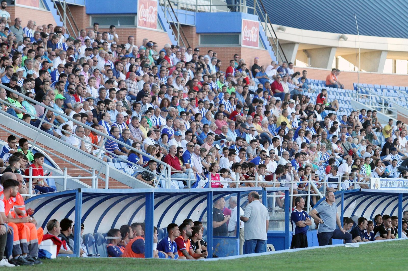 1. La zona de tribuna contó con una gran afluencia de público. 2. El alcalde, Gabriel Cruz, junto al presidente del Recreativo, Manolo Zambrano. 3. Varios recreativistas disfrutan del encuentro en la grada. 4. La grada 20 de Diciembre animó al cuadro albiazul durante todo el partido. 5. La Peña Recreativista de Hinojos se dio cita en el Nuevo Colombino. 6. Los jugadores suplentes se fotografían con un chico. 7-8. La afición del Recreativo conversa antes del inicio del choque. 9. El abuelo del Decano saluda a todos los presentes en el estadio.
