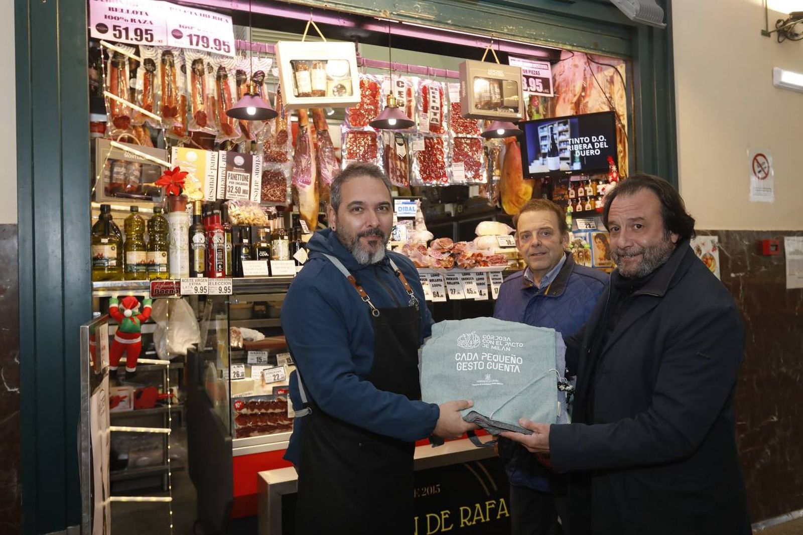 Daniel García-Ibarrola y Julián Urbano entregan bolsas de tela a la Charcutería El rincón de Rafa.