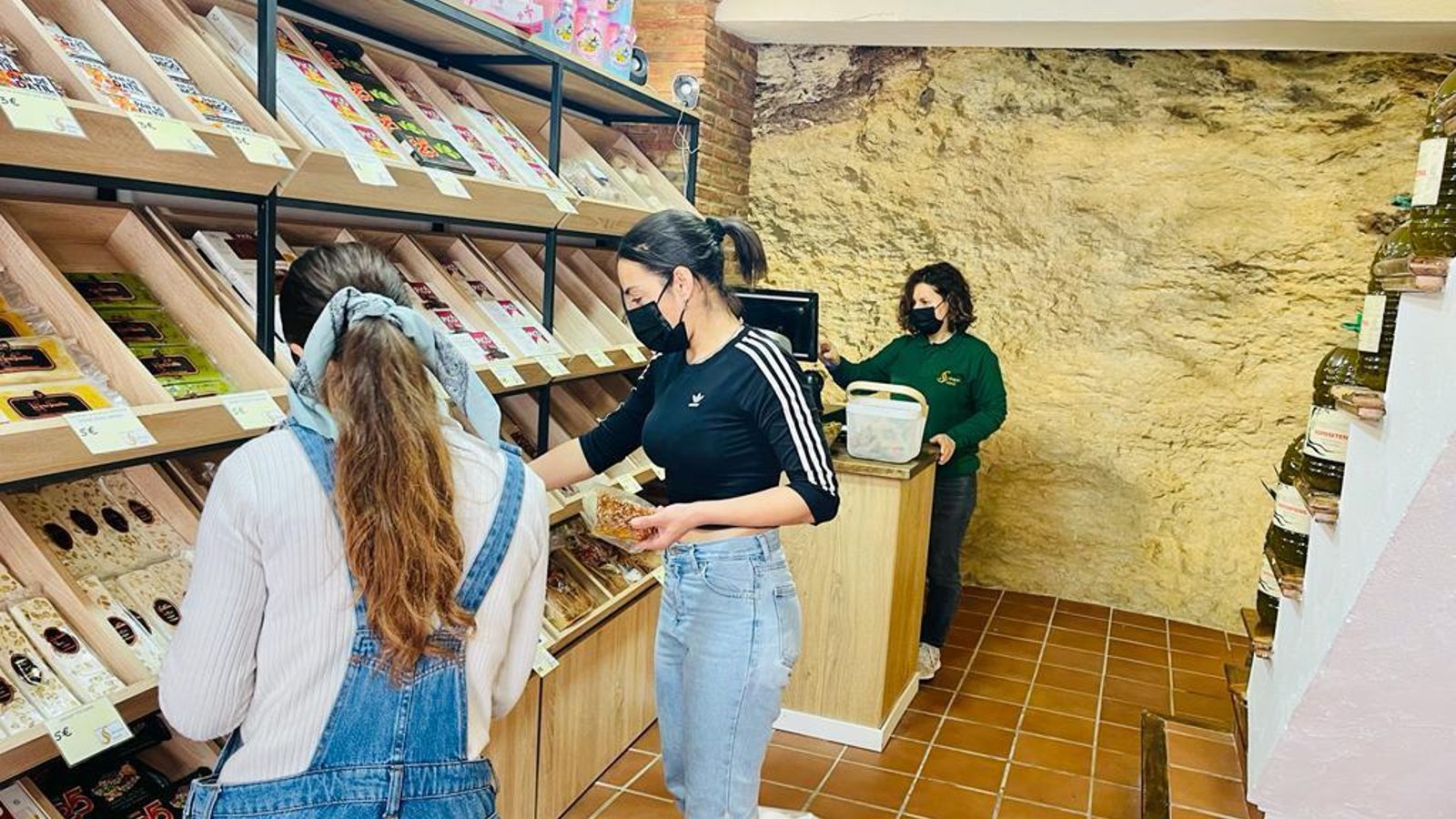 La dueña de La tienda Sabores de Setenil y varias clientas, un negocio abierto en una casa-cueva de Setenil.