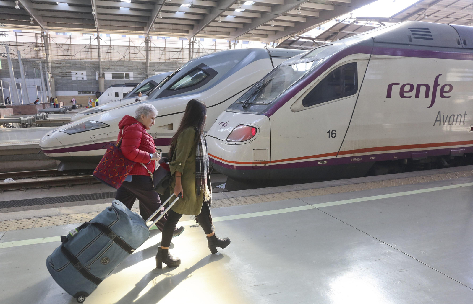 Dos viajeras pasan junto a un tren Avant y otro AVE.