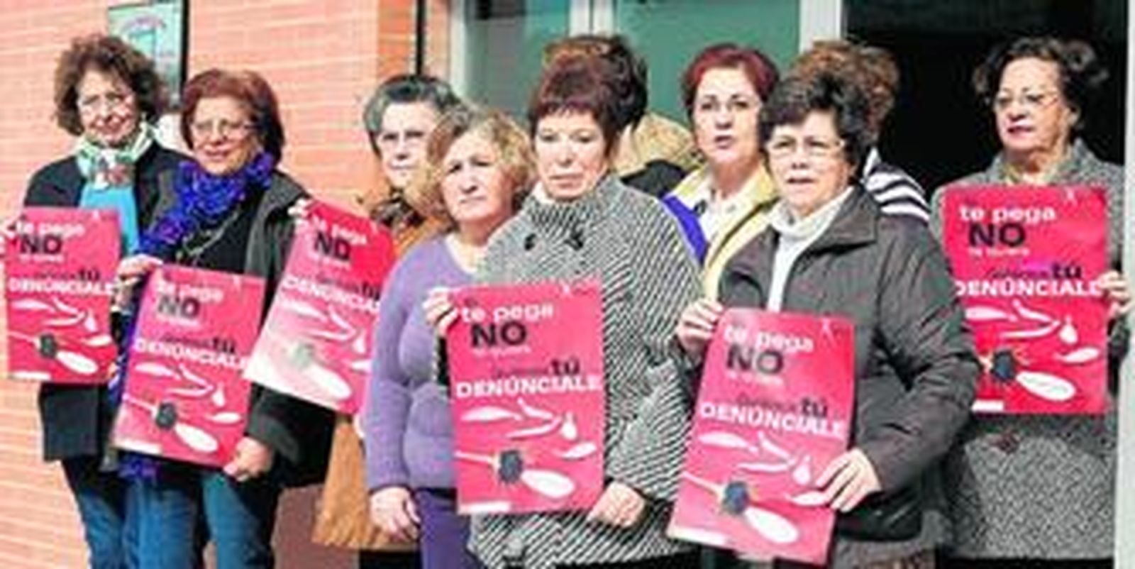 Algunas de las mujeres que han recibido el curso, en la sede de la AVV Antiguos Terrenos de Astilleros Cádiz, portando un cartel contra el maltrato.