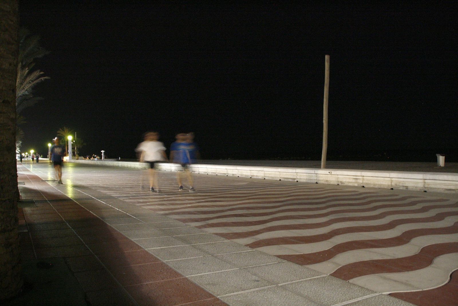 Varias personas recorren el paseo marítimo de la capital por la noche