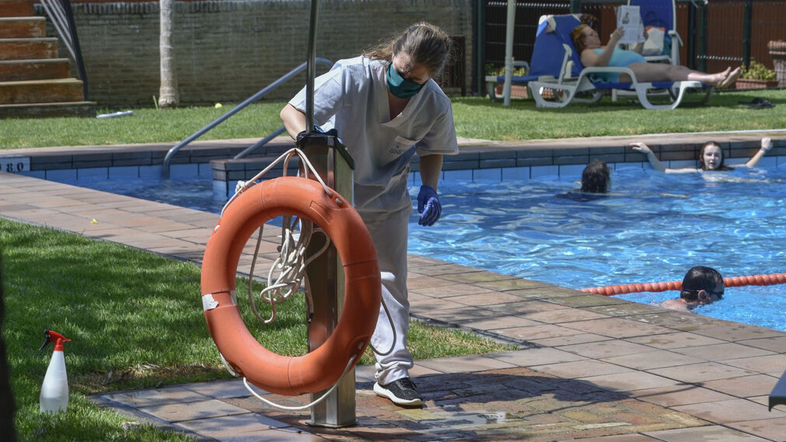 Una trabajadora limpia y desinfecta una piscina en Sevilla.