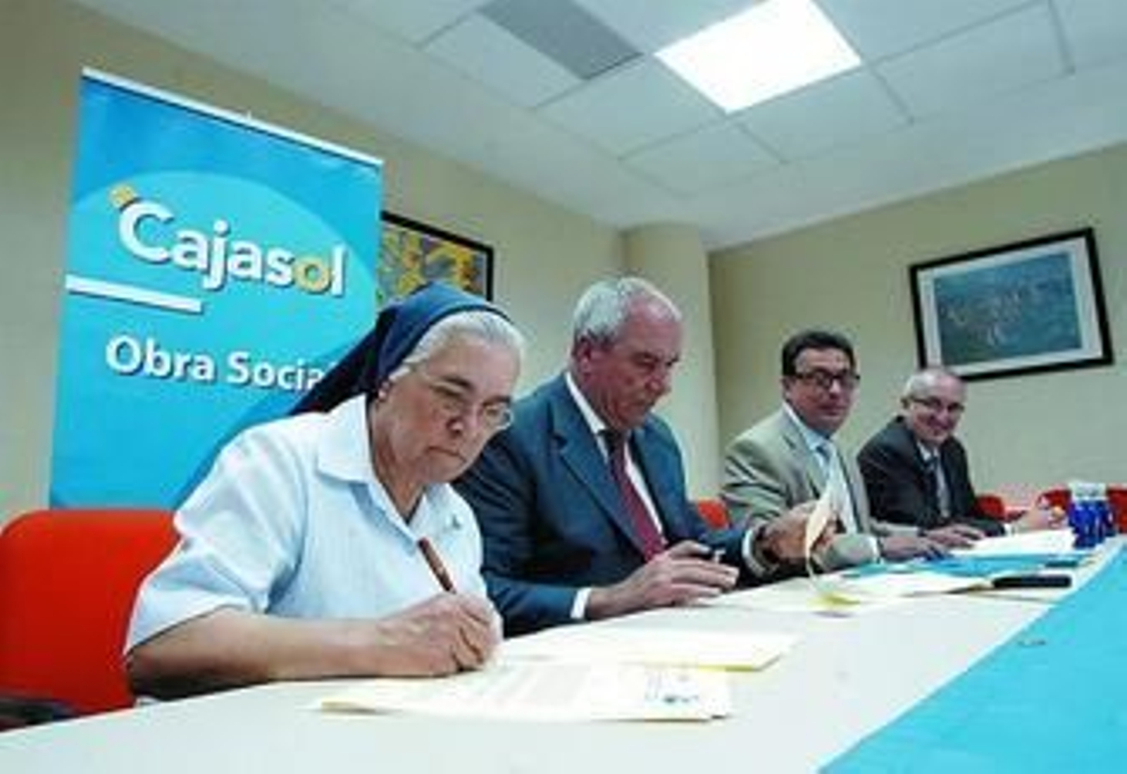 Sor Joaquina Aragón y Antonio Roldán, en primer término, suscriben uno de los convenios, ayer.