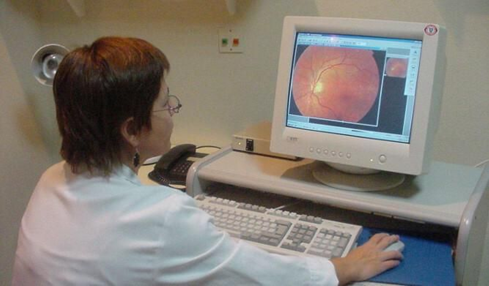 Una oftalmóloga estudia  una retinografía en su ordenador.