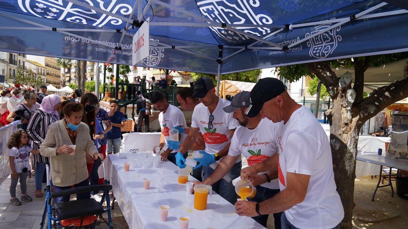 Varios participantes repartiendo zumo de naranja.