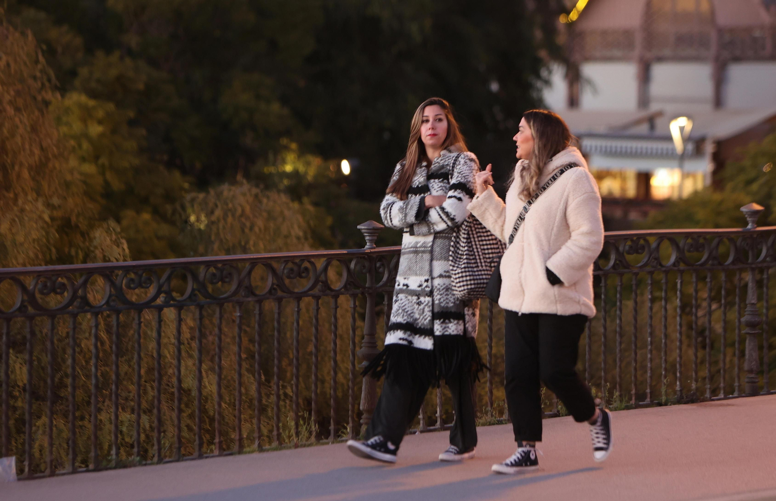 Dos mujeres abrigadas pasean por el puente de Triana