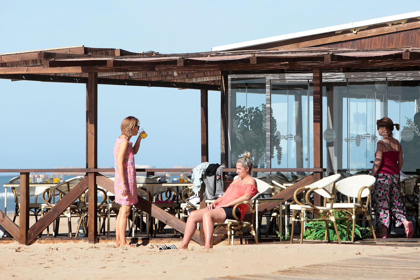 Unas clientas toman el sol en uno de los chiringuitos de la playa Victoria.