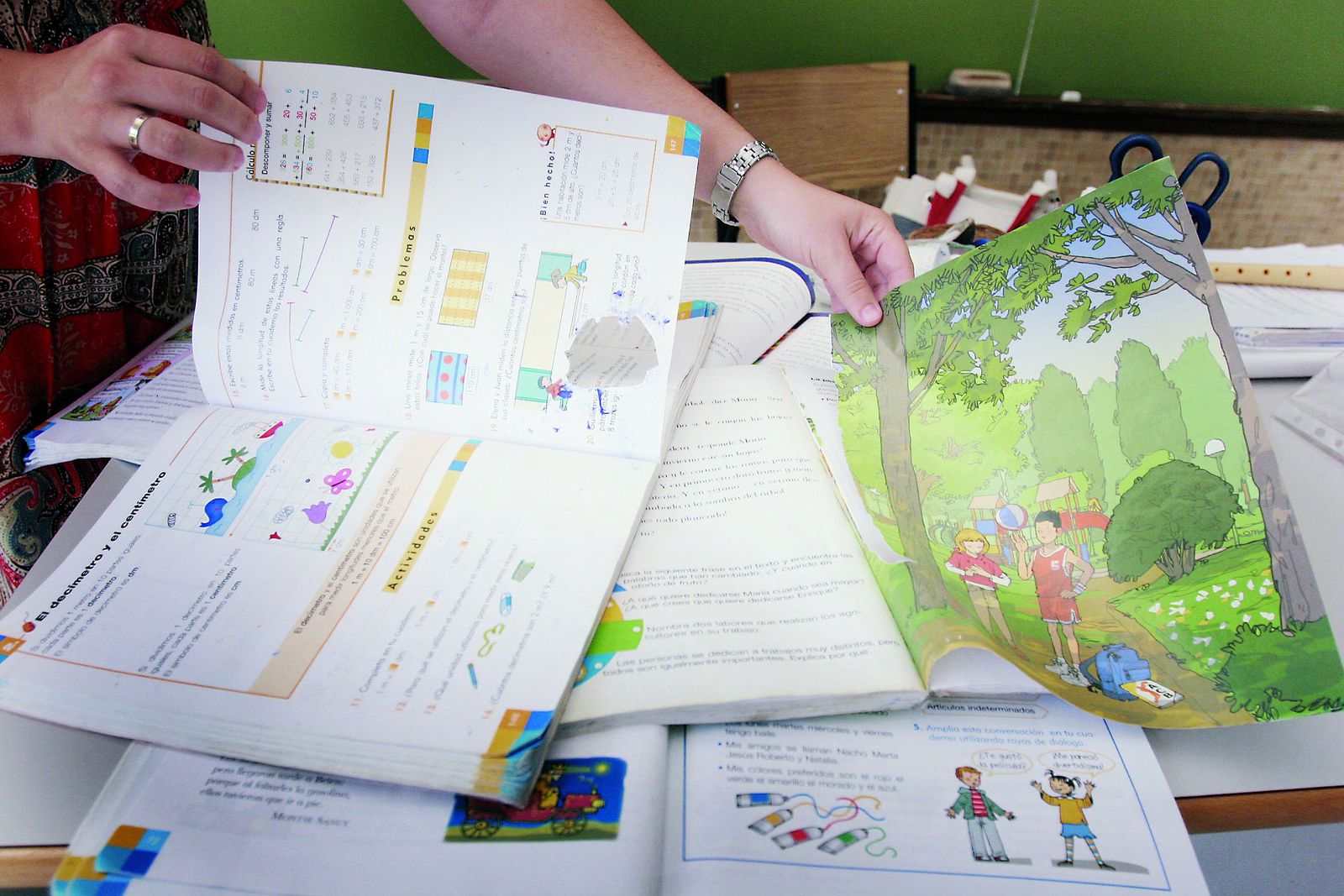 Una maestra enseña los libros de texto de Primaria.