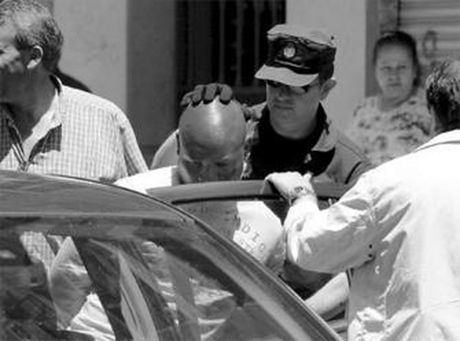 Uno de los detenidos en la operación policial entra en uno de los coches patrulla.