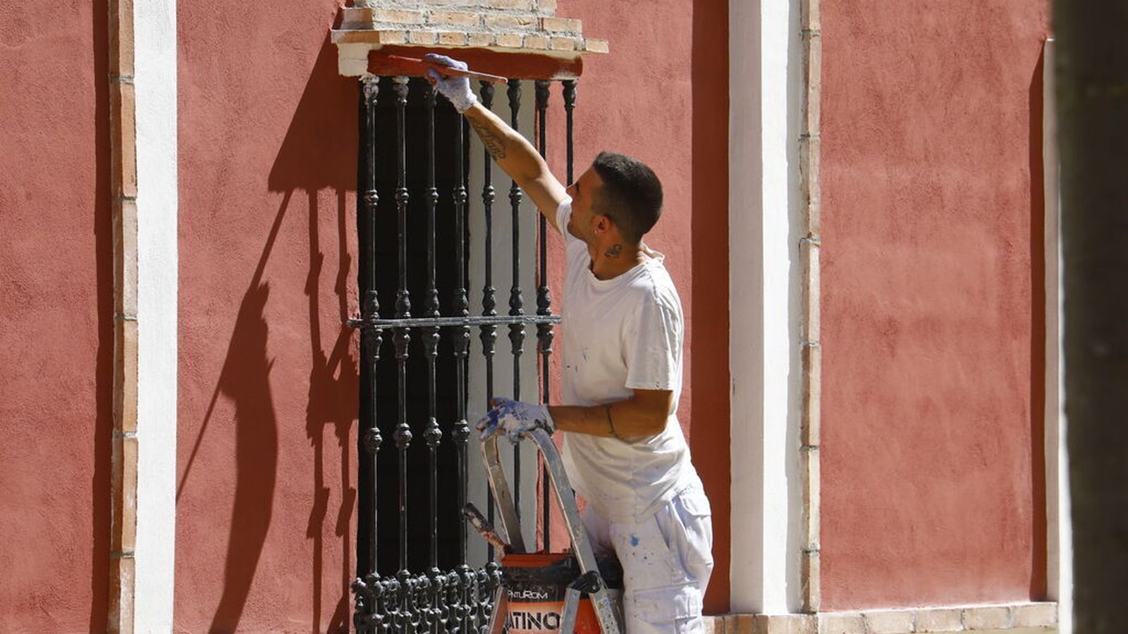 Un hombre termina de pinar la fachada de una caseta.