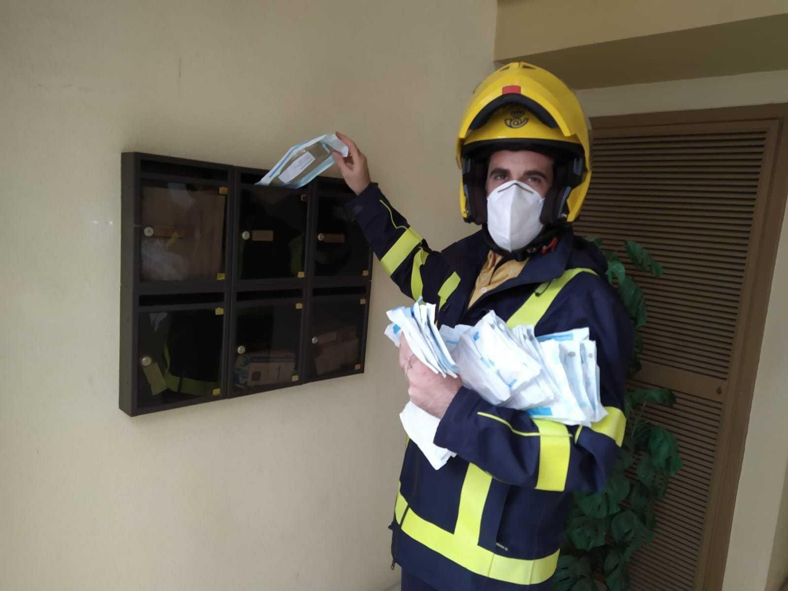 Un cartero deja una mascarilla en un buzón. Un cartero deja una mascarilla en un buzón.
