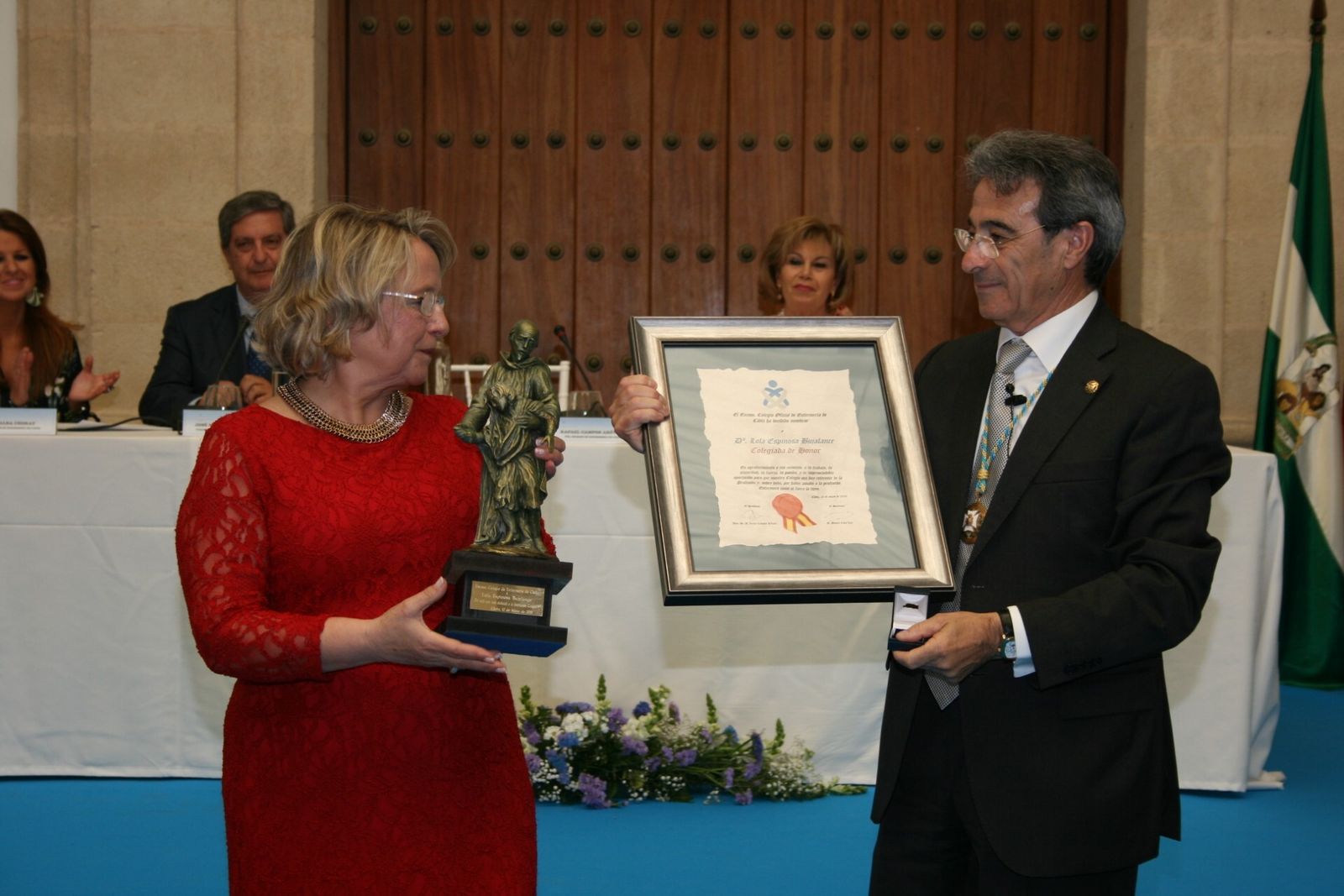 Dolores Espinosa recoge su título como Colegiada de Honor y la imagen del patrón de la profesión enfermera, San Juan De Dios, de manos del presidente del Colegio de Enfermería de Cádiz, Rafael Campos.