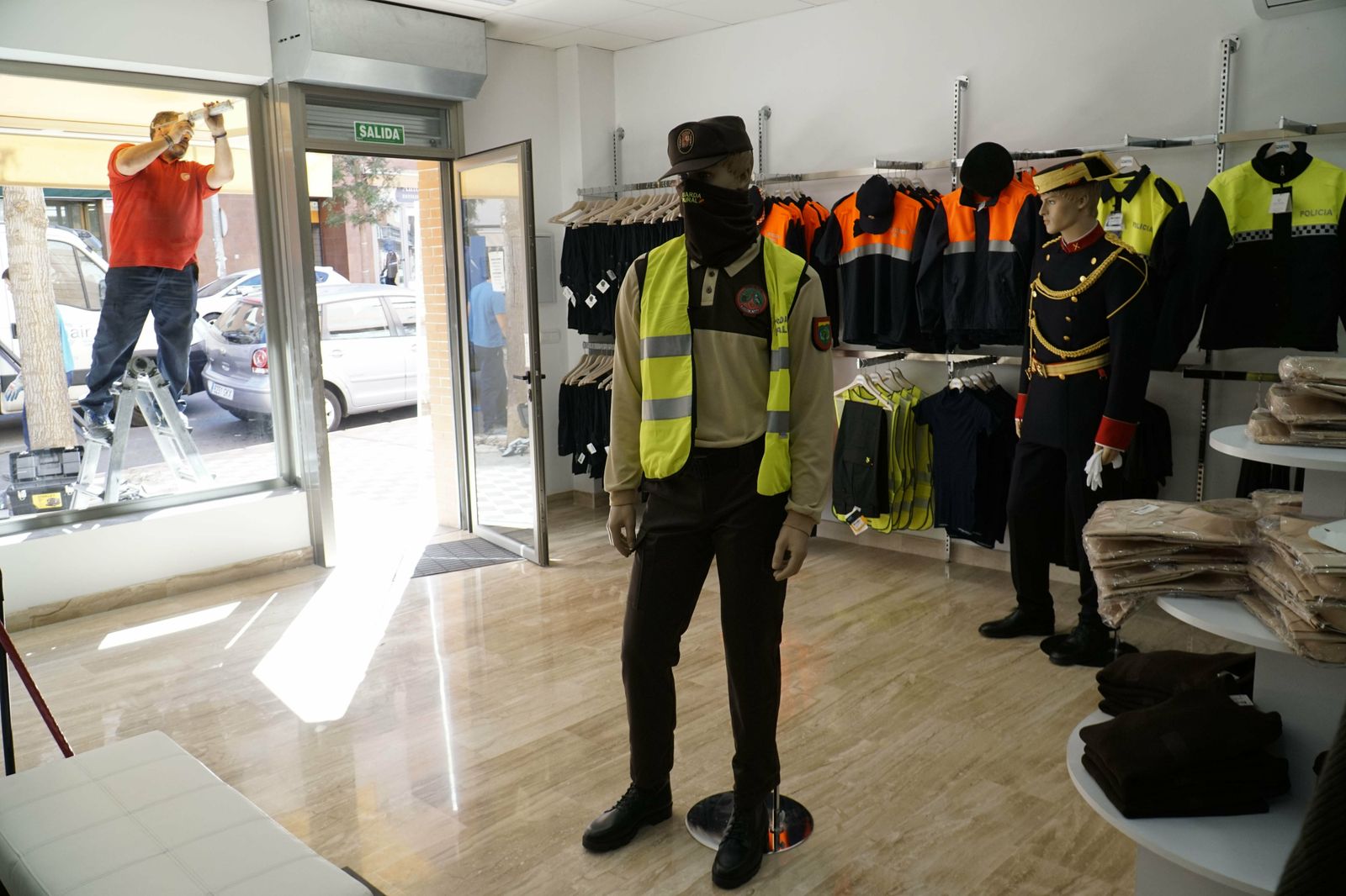 Un cristalero repone la luna del escaparate en la tienda de uniformes Manufacturas Moya, este viernes.