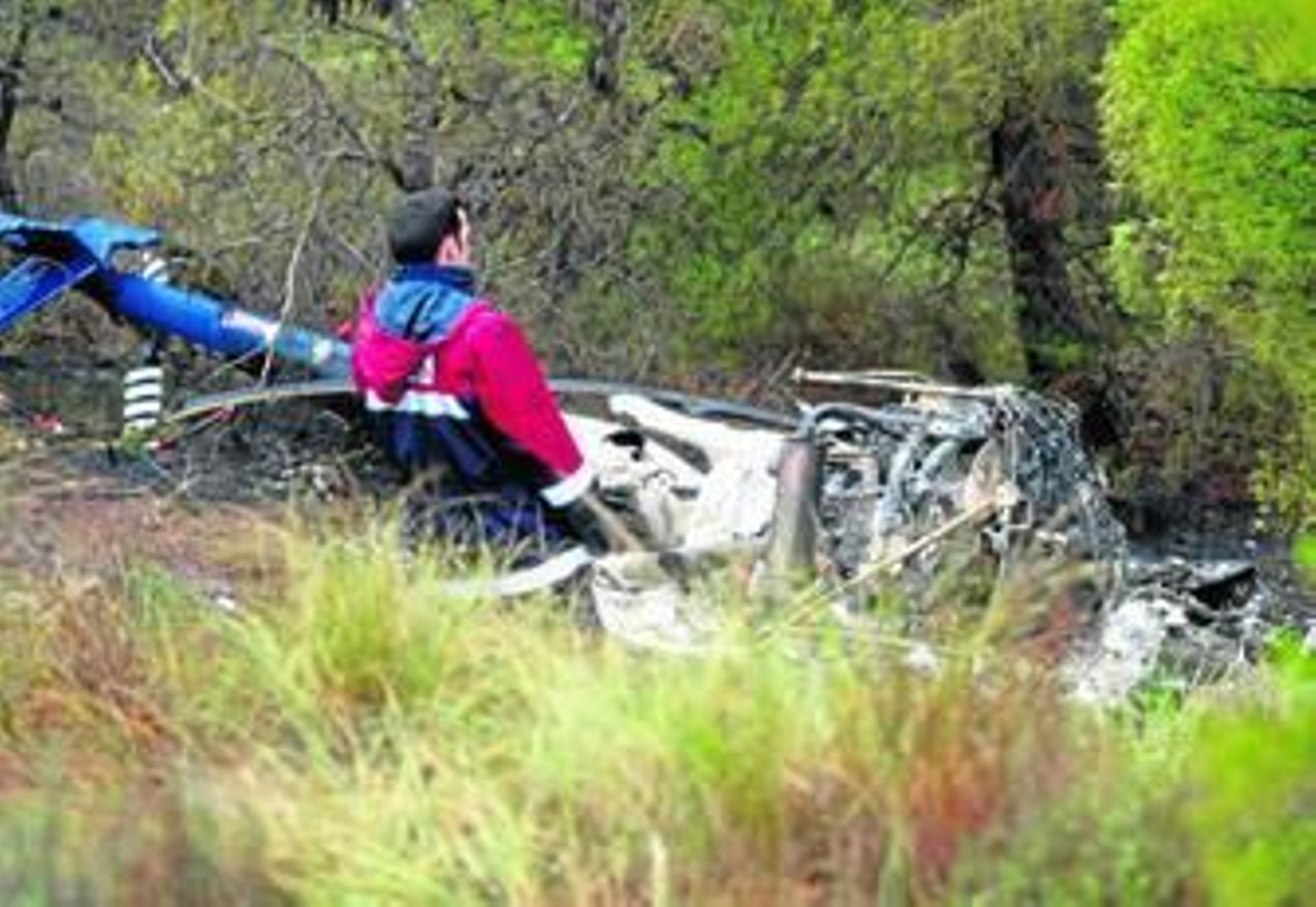 Un miembro de los equipos de rescate, junto al helicóptero siniestrado.