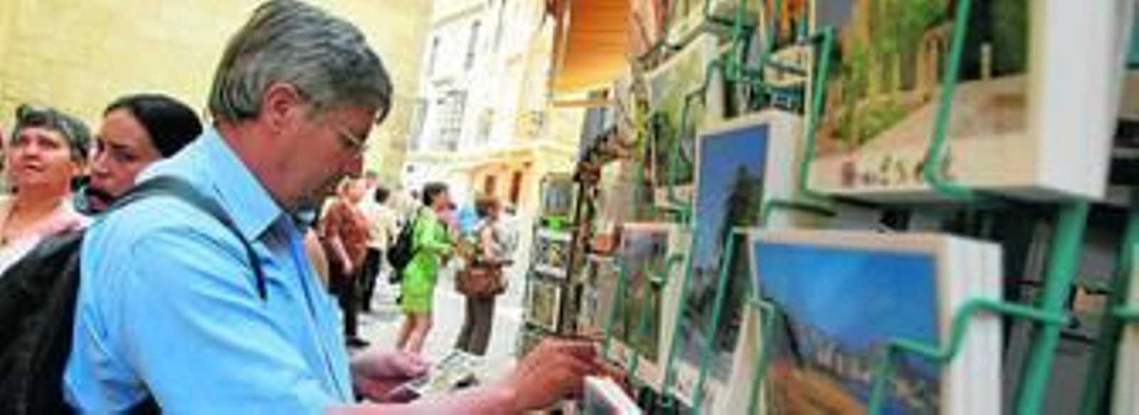 Un turista observa unas postales en un comercio situado junto al Museo Picasso.