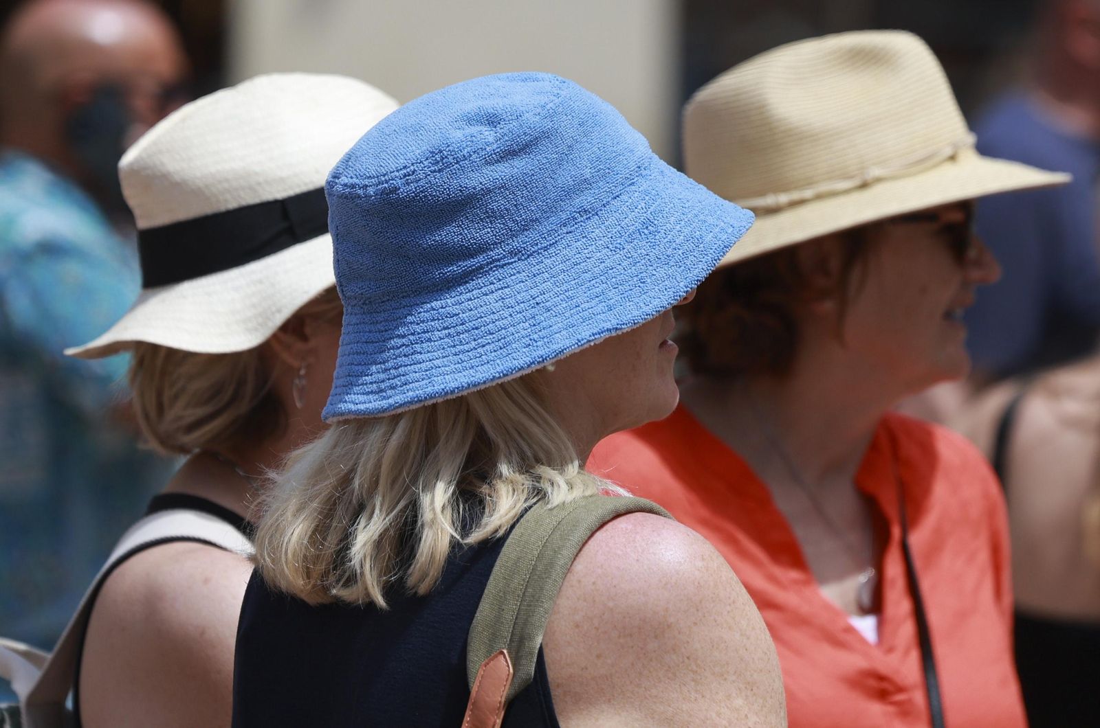Tres mujeres se protegen del sol en Málaga con unos sombreros.