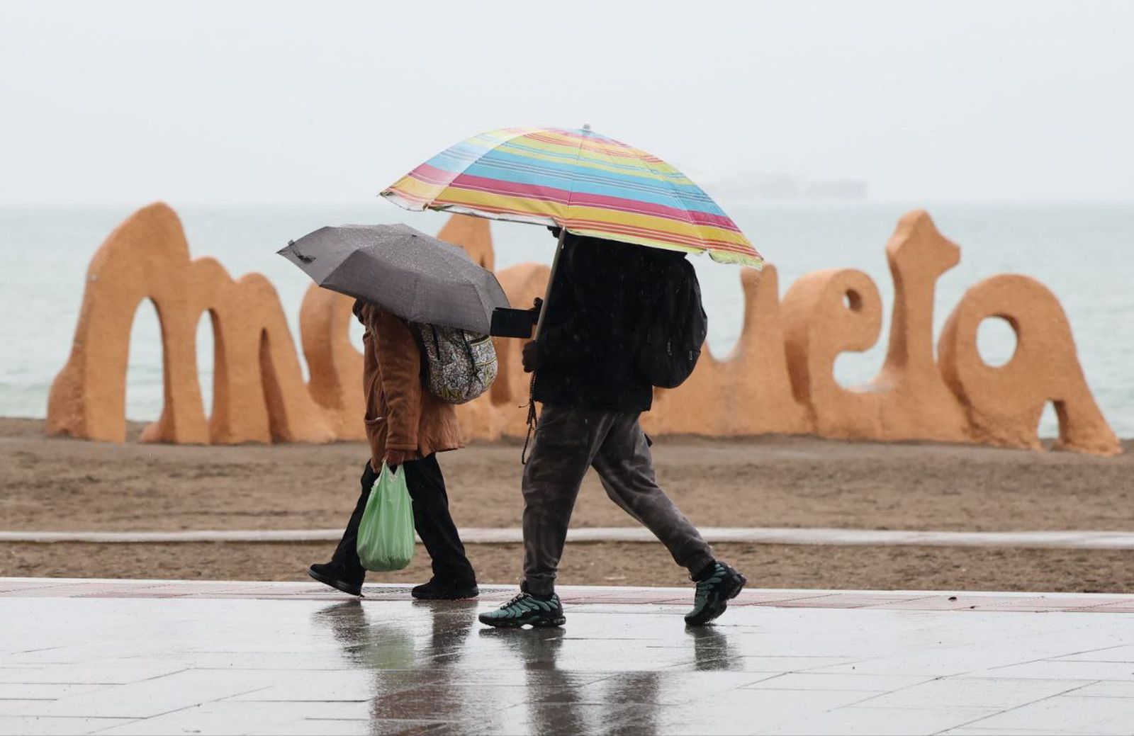 Dos personas se protegen de la lluvia en Málaga.