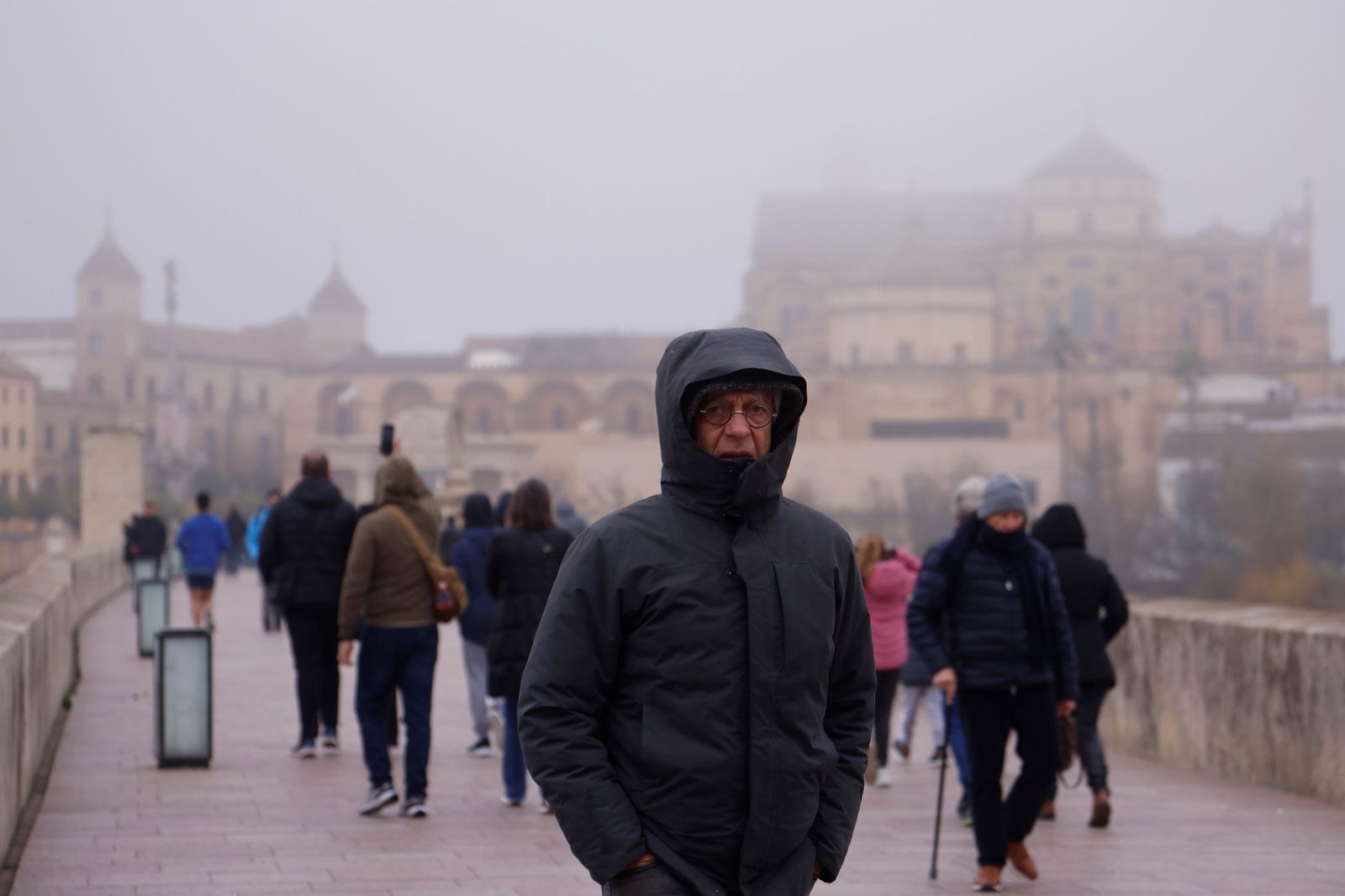 Un hombre camina muy abrigado por el Puente Romano.