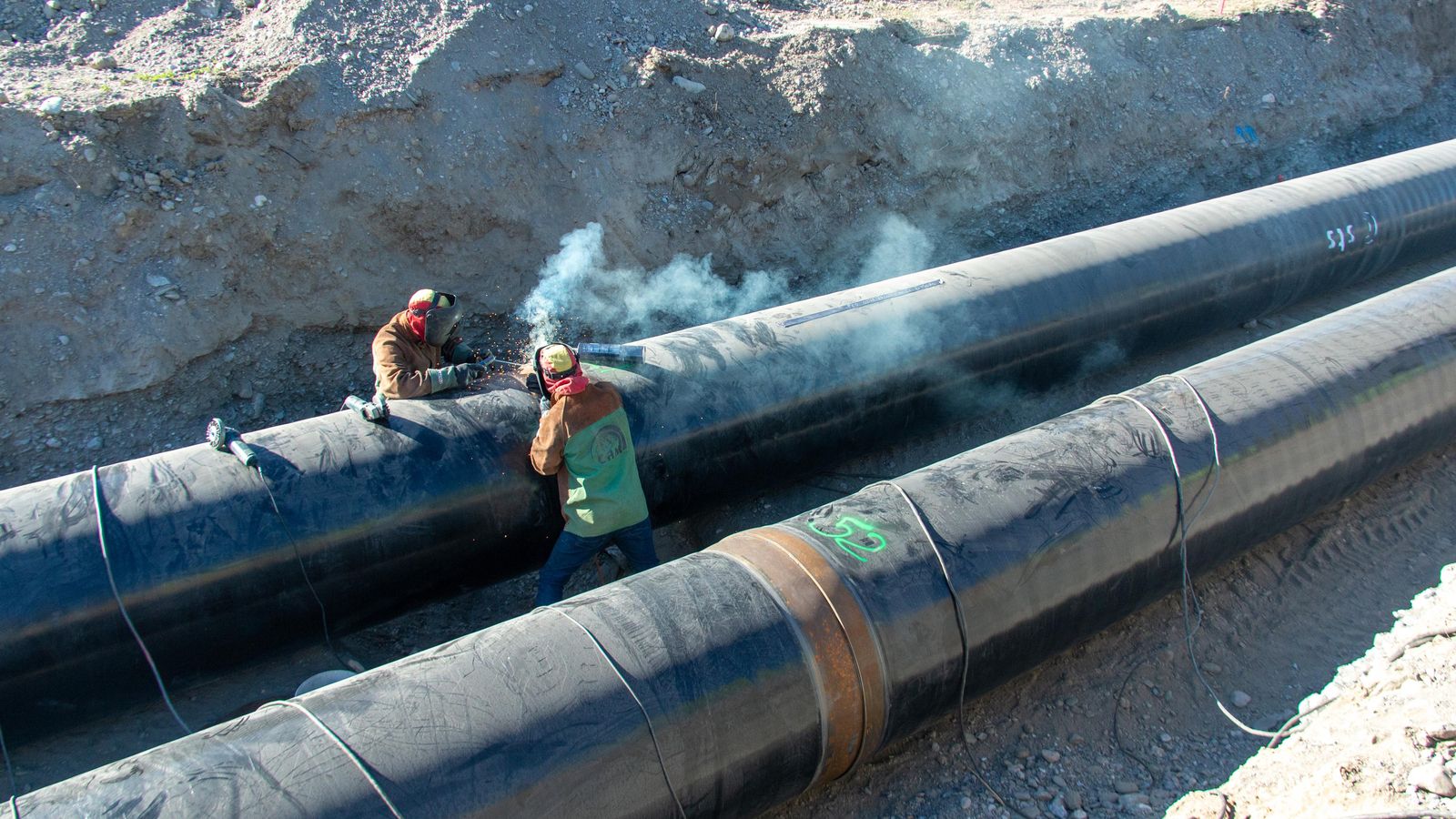 Dos trabajadores soldando dos de las tuberías