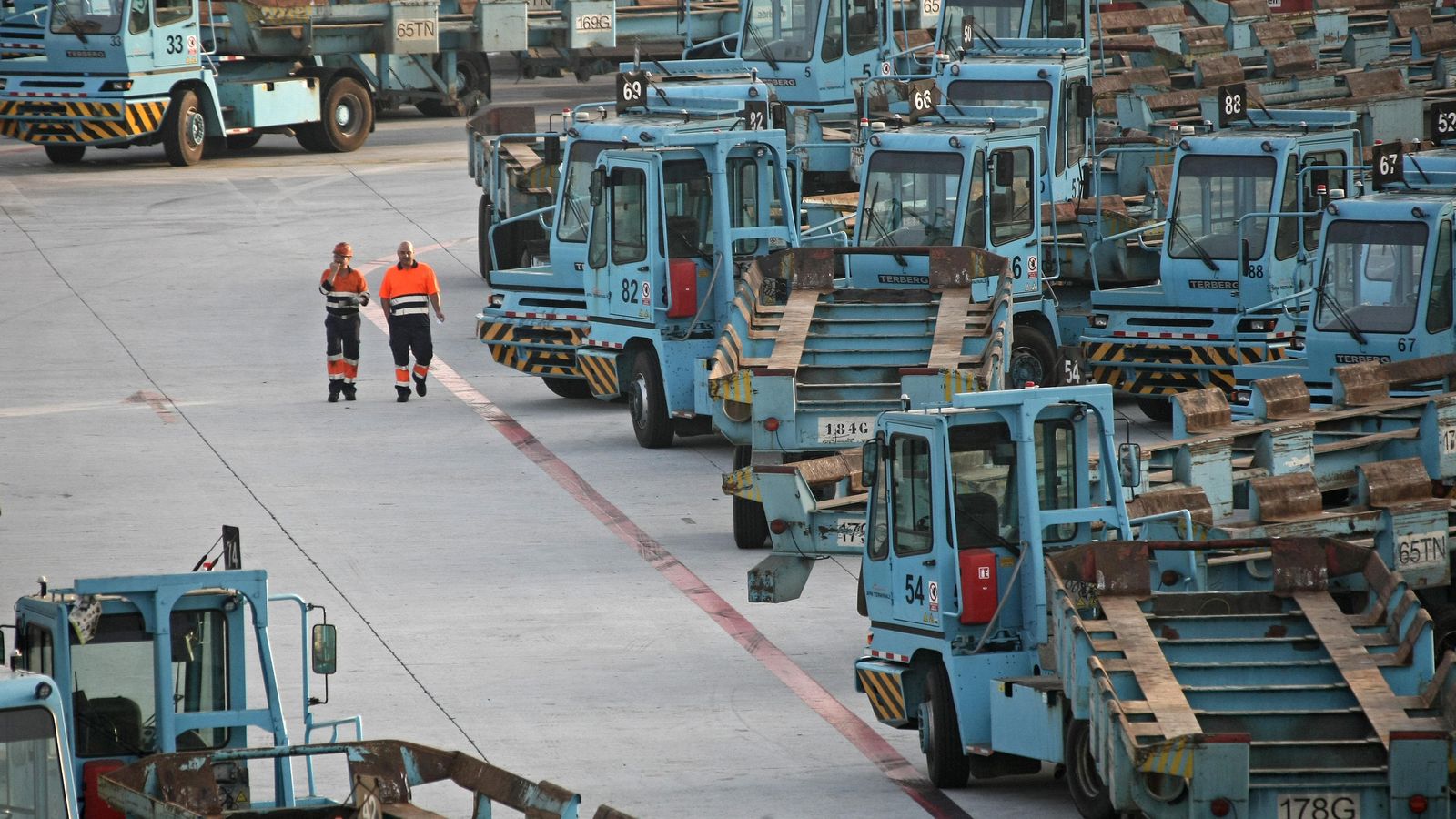 Dos estibadores del Puerto de Algeciras caminan junto a la maquinaria.
