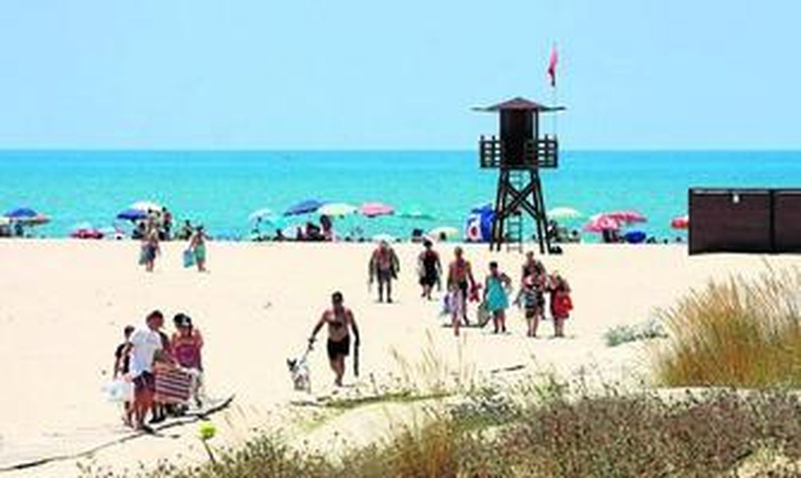 Bañistas se dirigen a una de las playas de la provincia de Huelva a principios de verano.