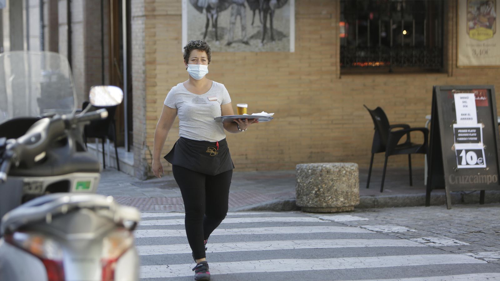 Una camarera cruza con una bandeja un paso de peatones.