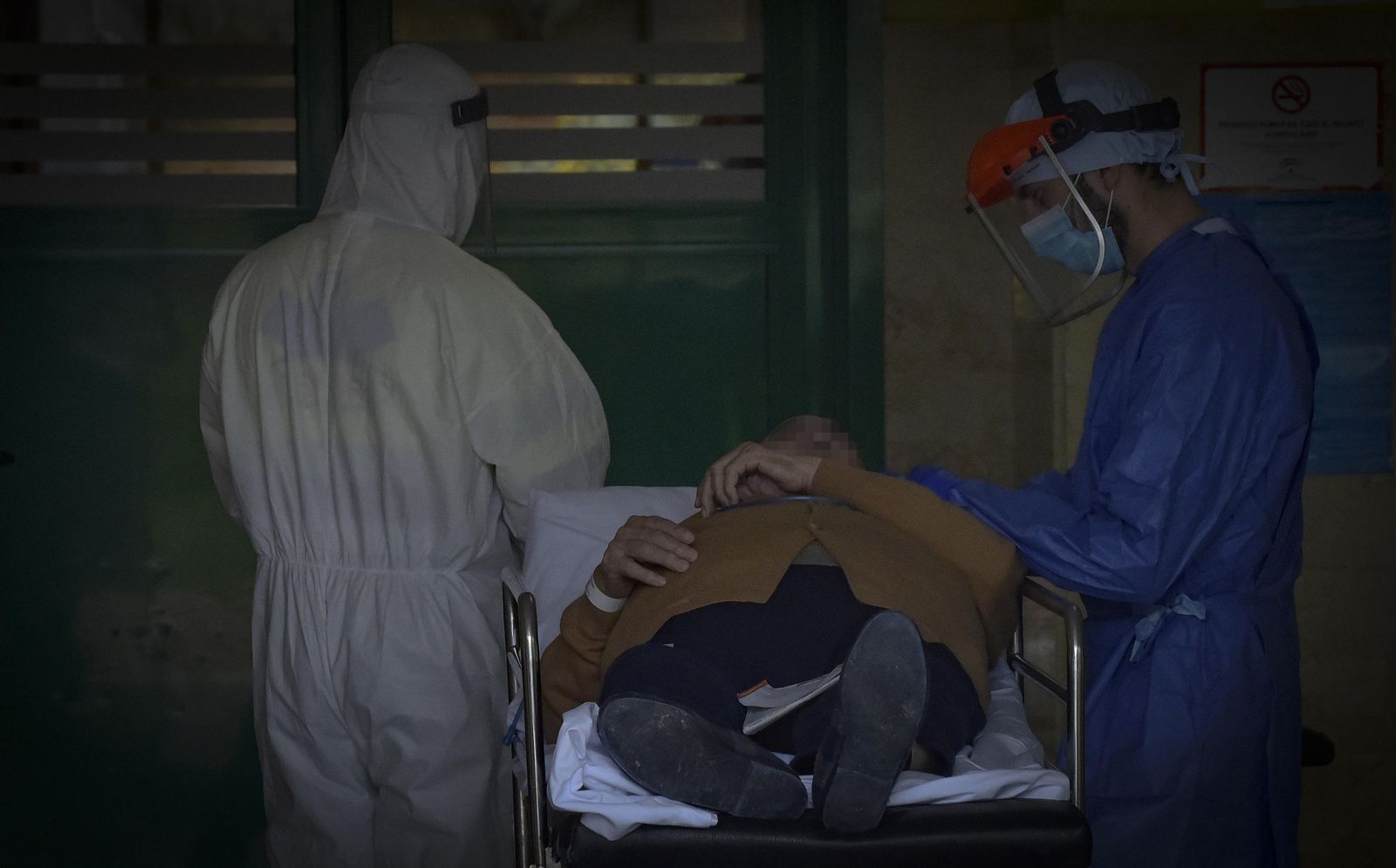 Dos sanitarios  junto a un paciente en el momento de su hospitalización en un centro sevillano.