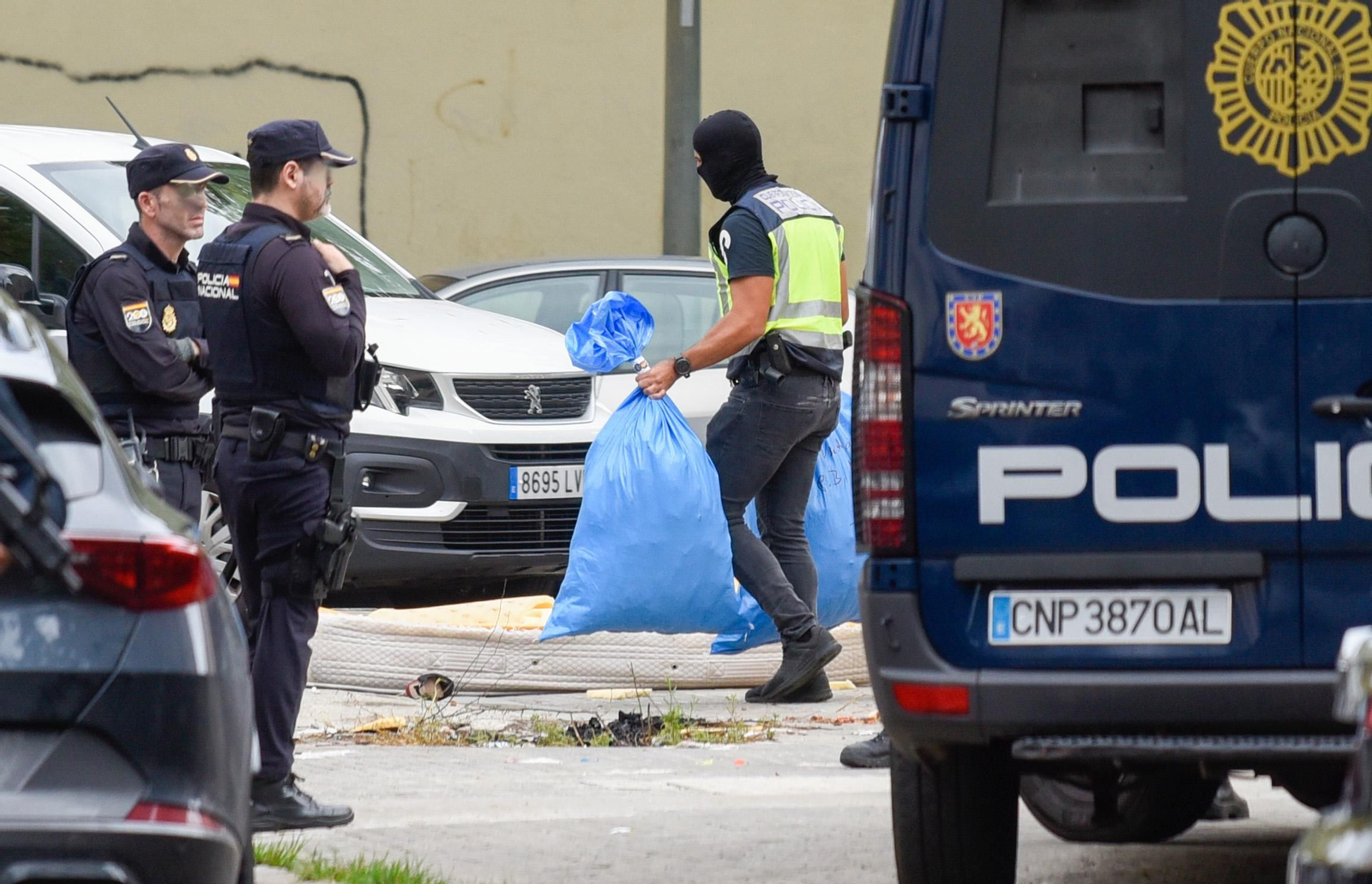 Un policía nacional saca dos bolsas con plantas de marihuana, en una redada en las Tres Mil Viviendas.