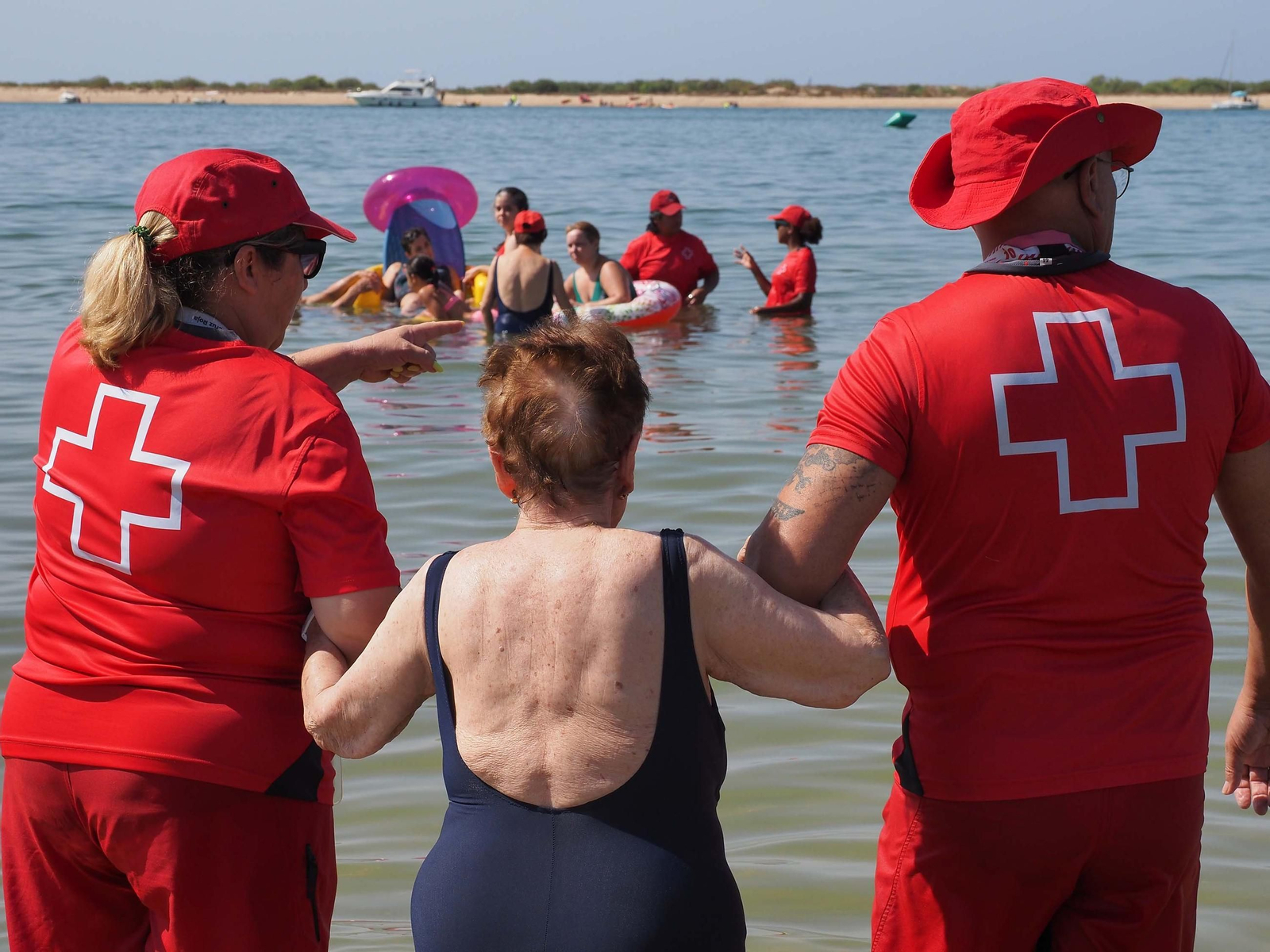Voluntarios de Cruz Roja asisten a varias personas en la playa del Caño de la Culata (Cartaya), este martes