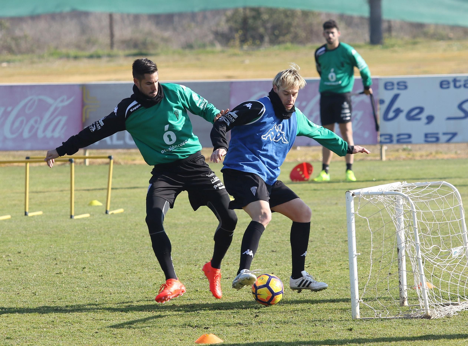Javi Lara disputa un balón con Luso en un entrenamiento, mientras Caro observa la jugada al fondo.