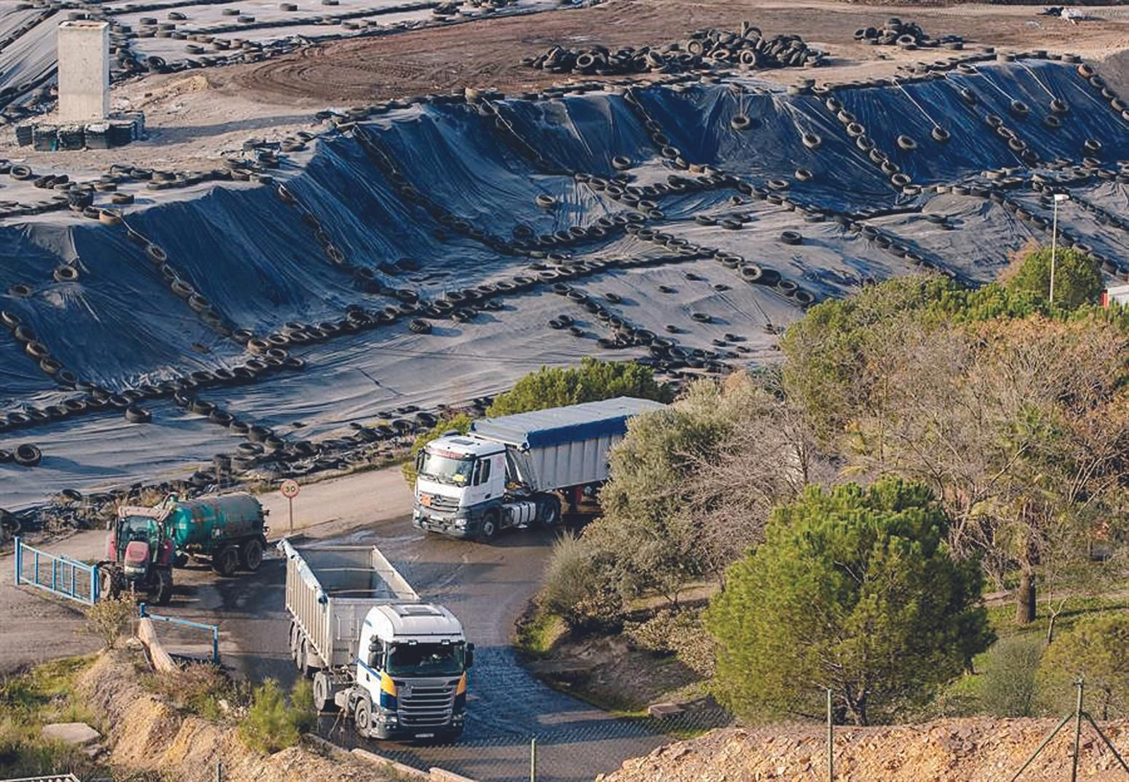 Dos camiones tras dejar su carga salen del vertedero de residuos tóxicos de Nerva.