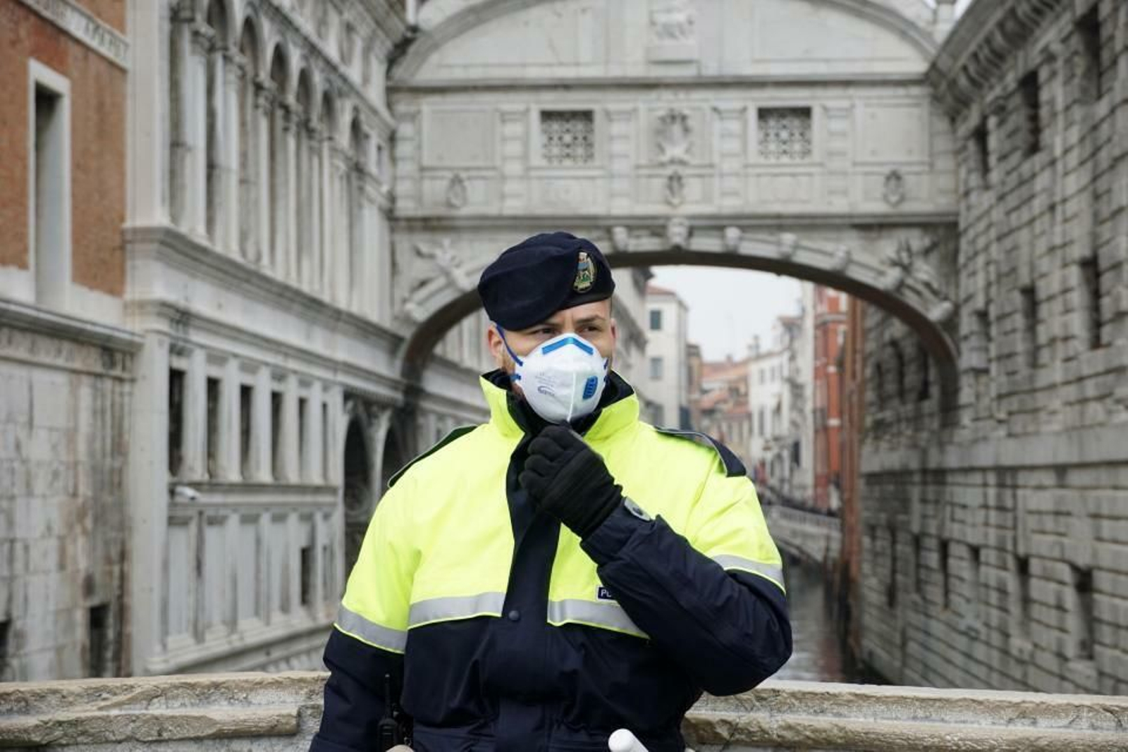 Un policía se protege con mascarilla frente a uno de los famosos puentes de Venecia.