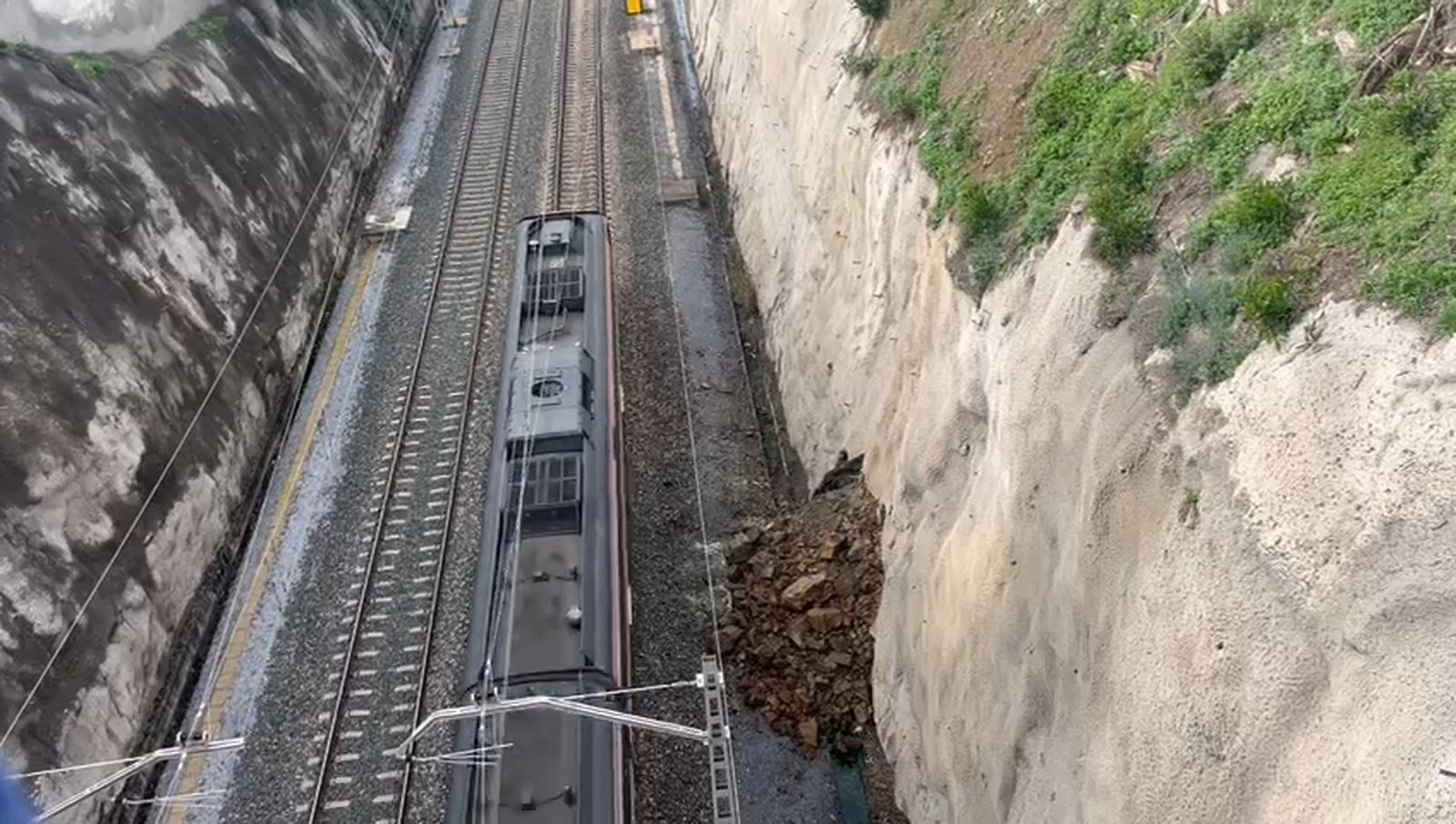 Un tren de Cercanías pasa junto al muro desprendido en Benalmádena