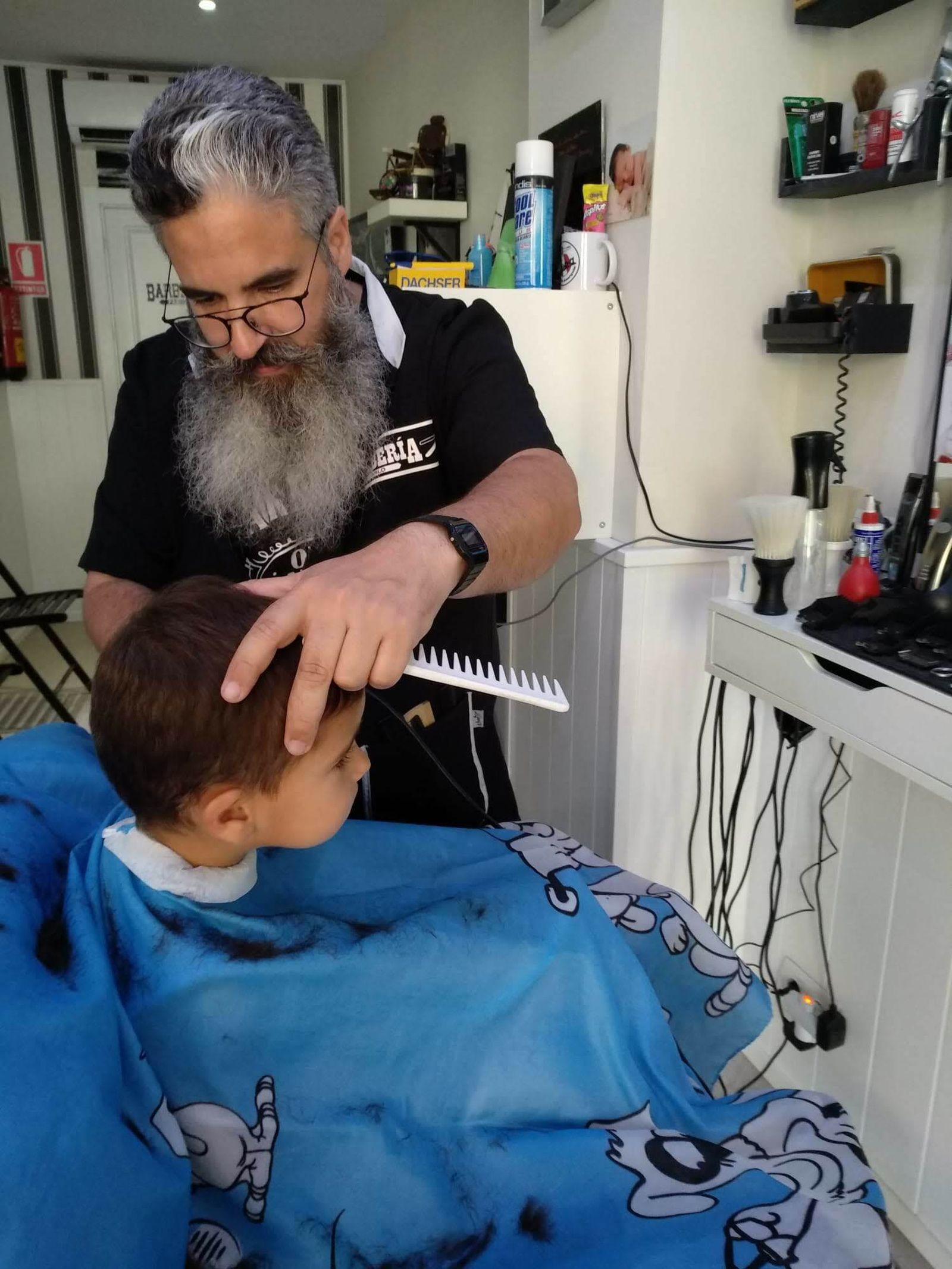 Pablo con un pequeño cliente que está deseando crecer lo suficiente para que puedan afeitarle.