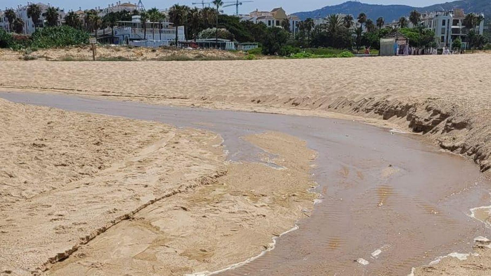 El riachuelo de aguas contaminadas en la playa de Atlanterra.