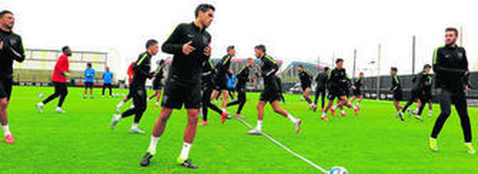 Los jugadores del Málaga, ayer, ejercitándose con e Nuevo Gasómetro de fondo.