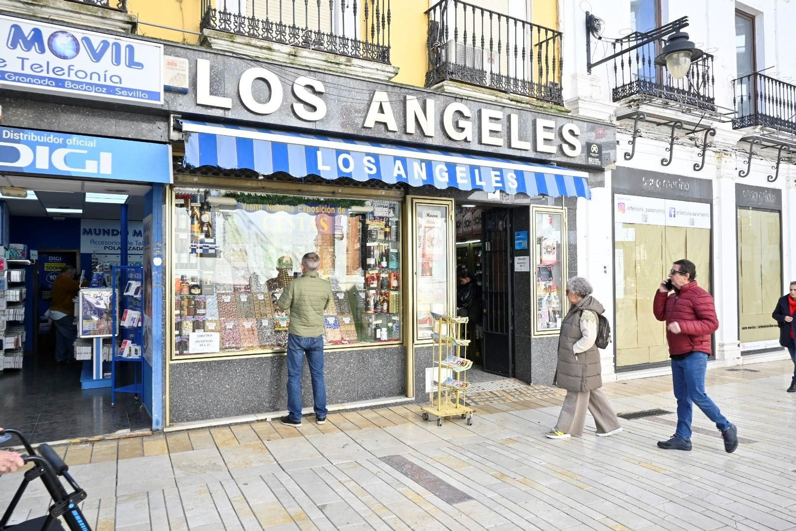 Varias personas se detienen frente a la puerta de Los Ángeles para ver su escaparate navideño.