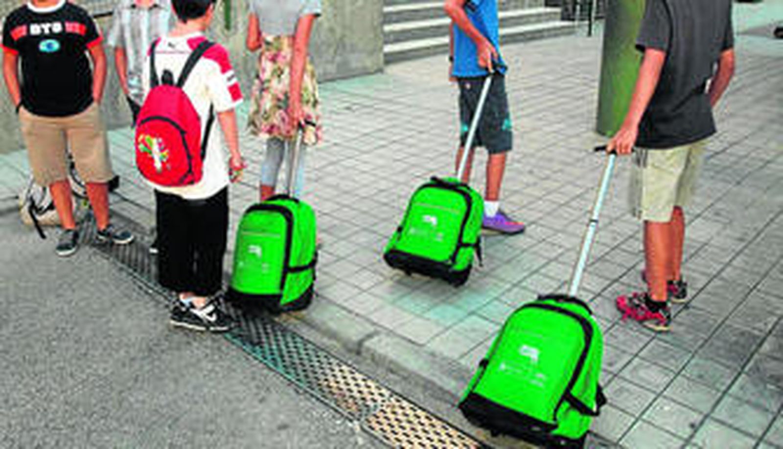 Alumnos de sexto de Primaria llegan al colegio con las mochilas que les regaló el pasado curso el Gobierno andaluz con los portátiles.