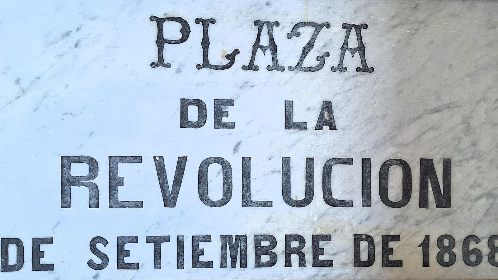 Lápida de mármol con el título que ostentó la plaza de Santa María durante el Sexenio Revolucionario (1868-1874).