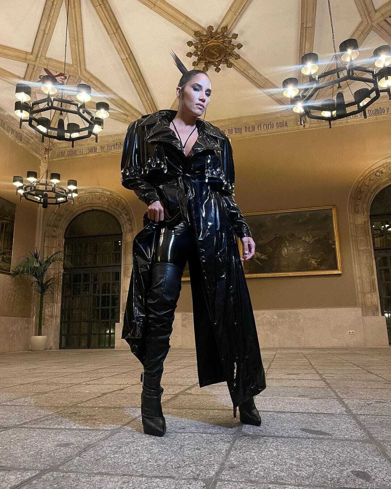 La cordobesa sorprende en el vídeo con un segundo estilismo muy distinto en charol negro con una espectacular gabardina XXL y botas de mosquetera