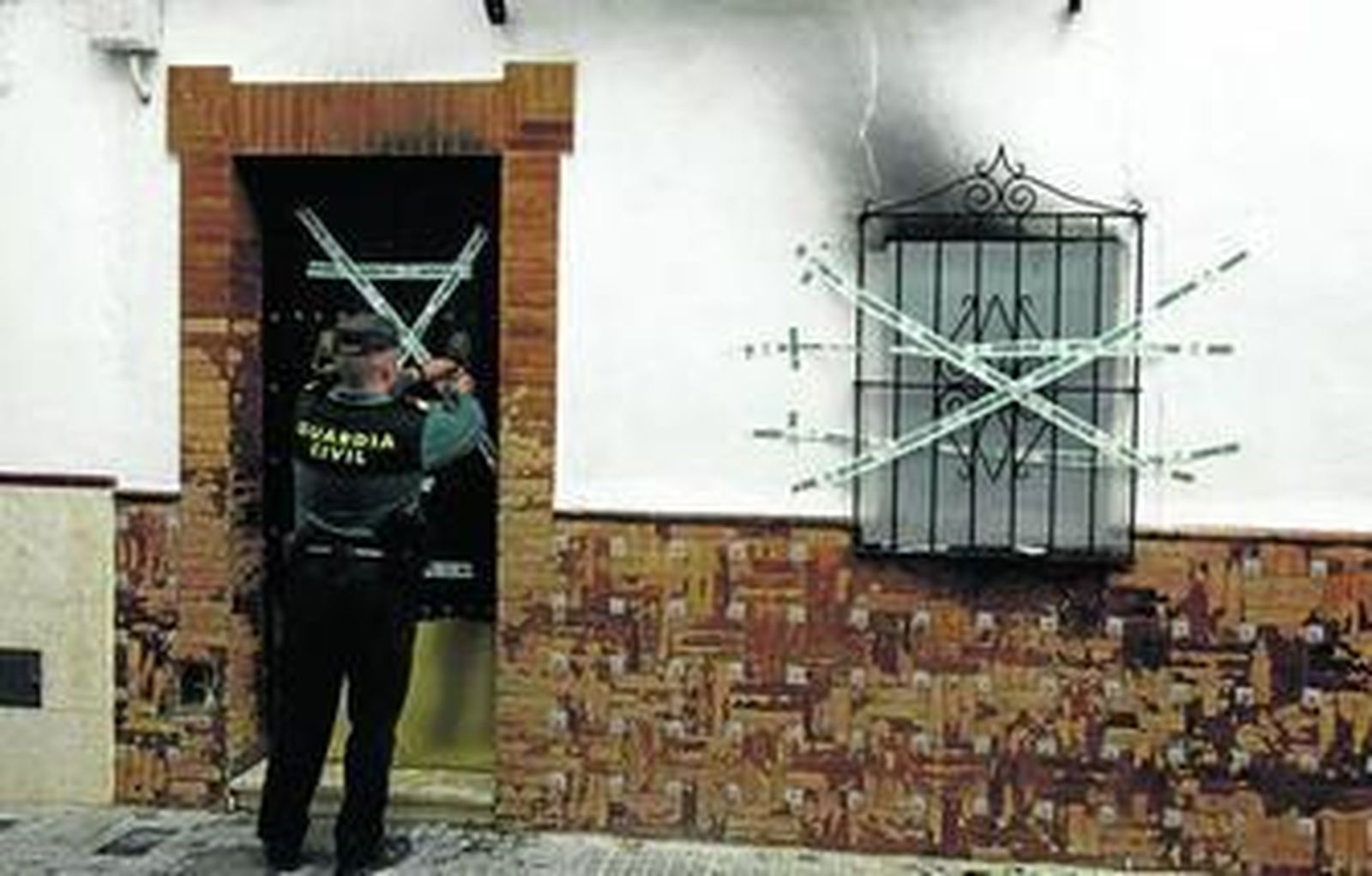 Un guardia civil precinta la casa de Arahal en la que murieron cuatro personas.