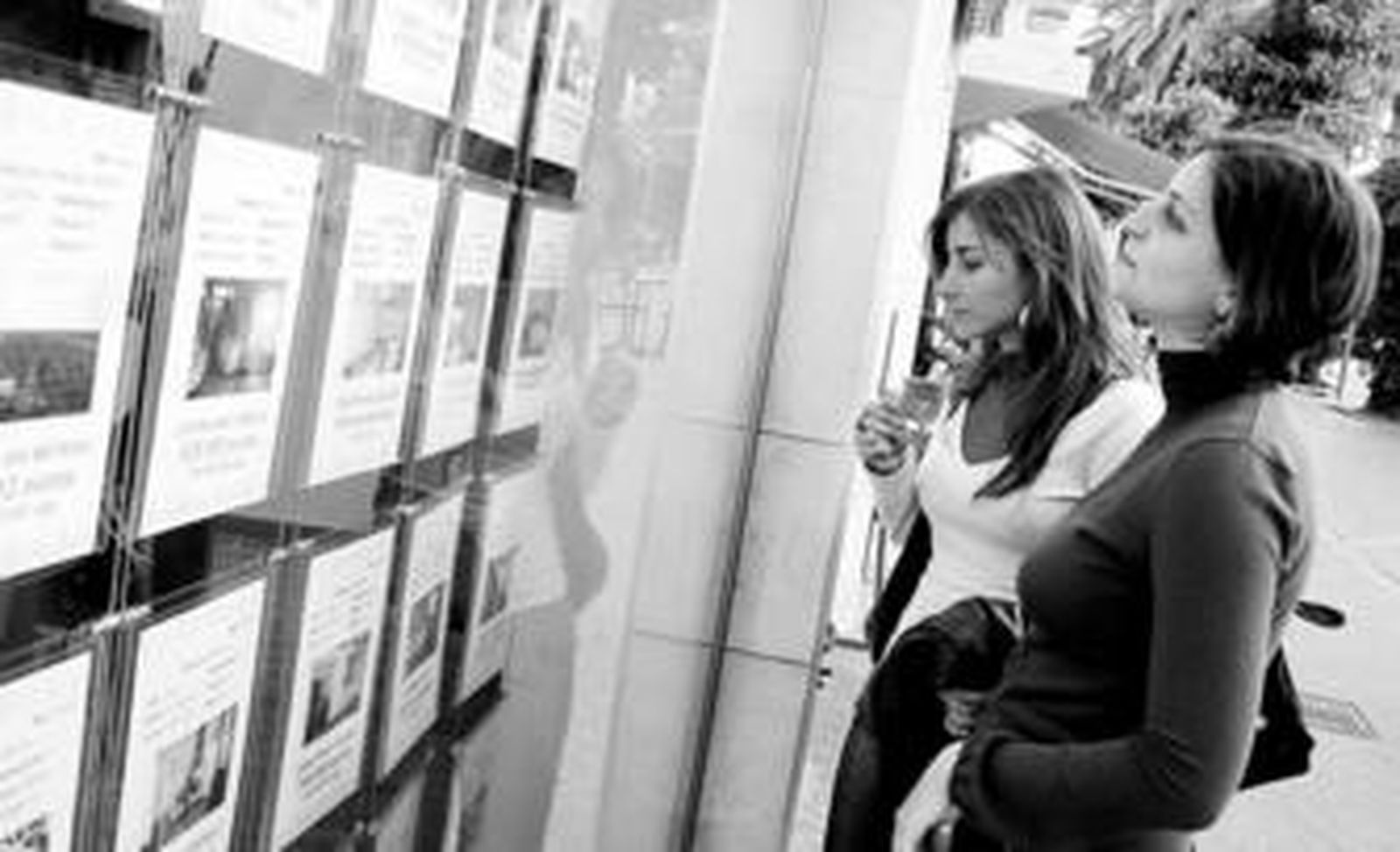 Dos jóvenes comparando ofertas de alquiler de pisos.