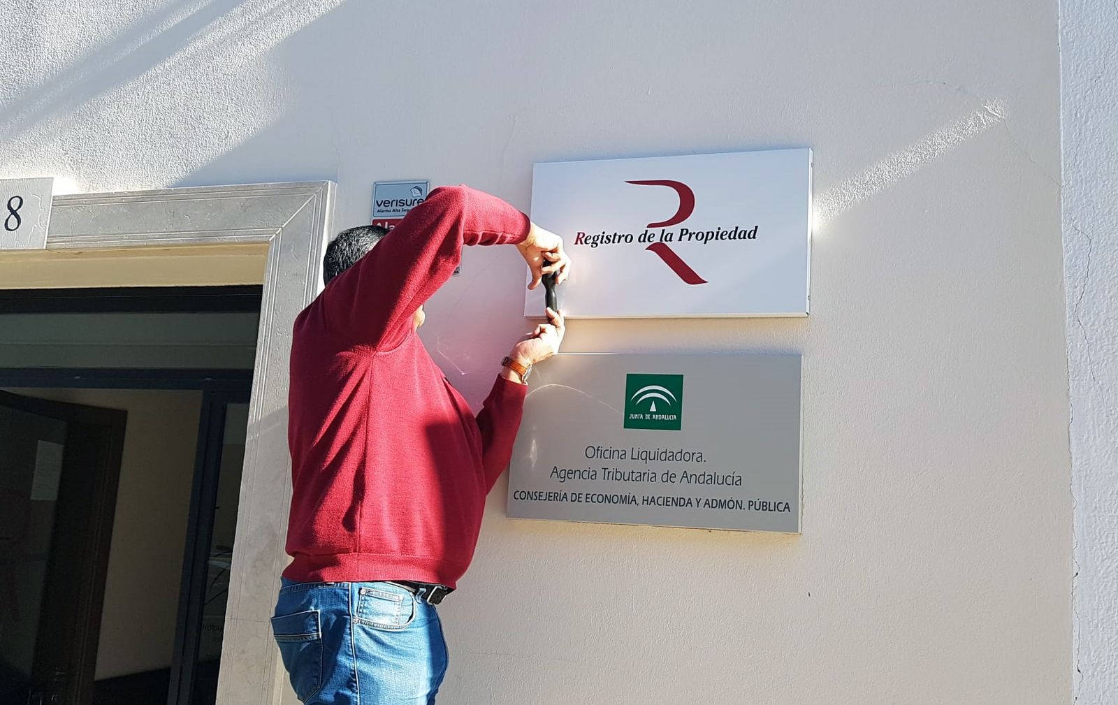 Un registrador de la propiedad retira el cartel de una oficina liquidadora.