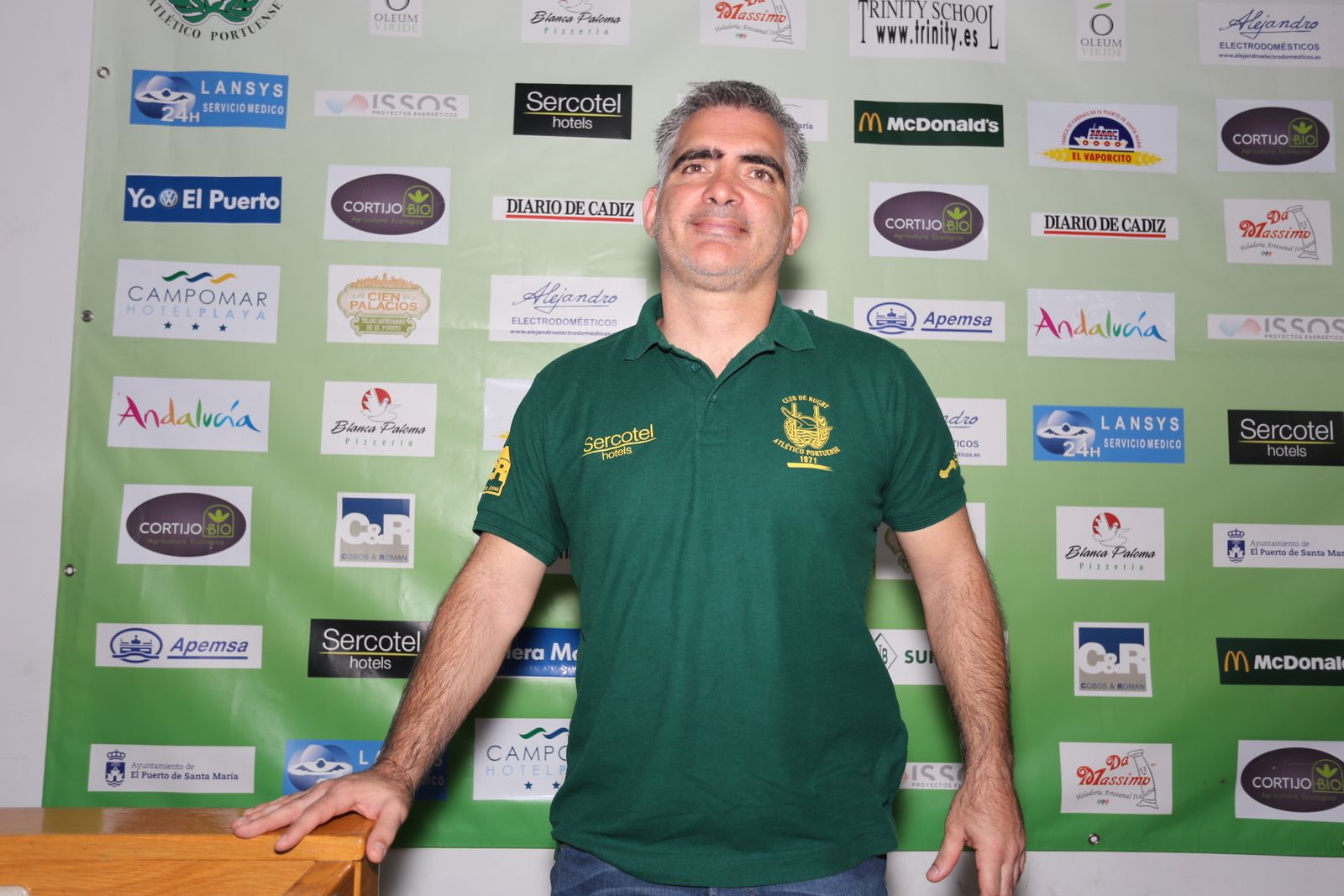El entrenador del CRAP, Guzmán Álvarez, posa en la sede del club junto al cuadro de patrocinadores.