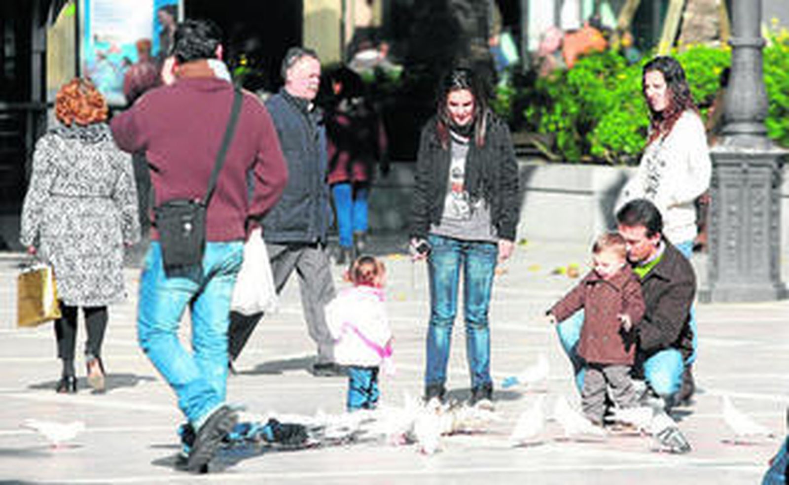 Dos niños juegan con palomas en la Plaza de las Monjas de la capital onubense.