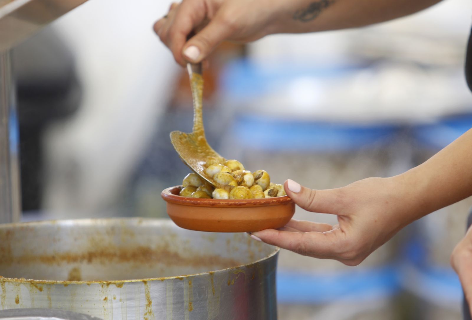 Una mujer sirve un cuenco de caracoles.