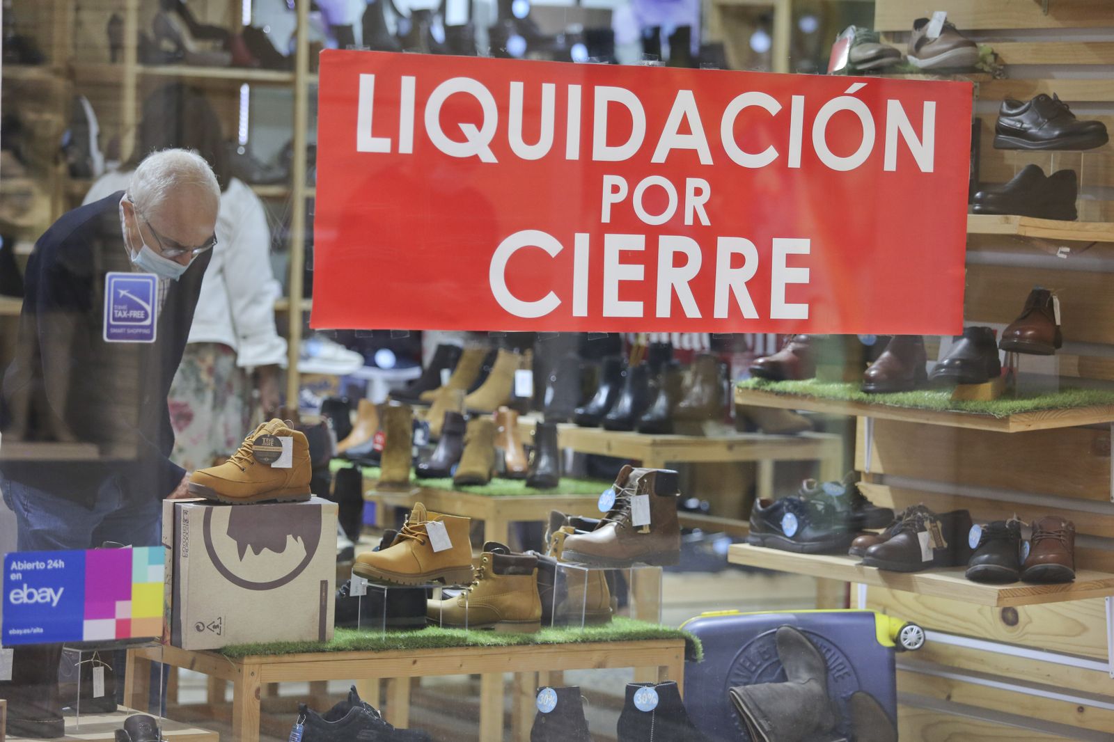 Un hombre mira los artículos de una zapatería de Málaga que anuncia el cierre.